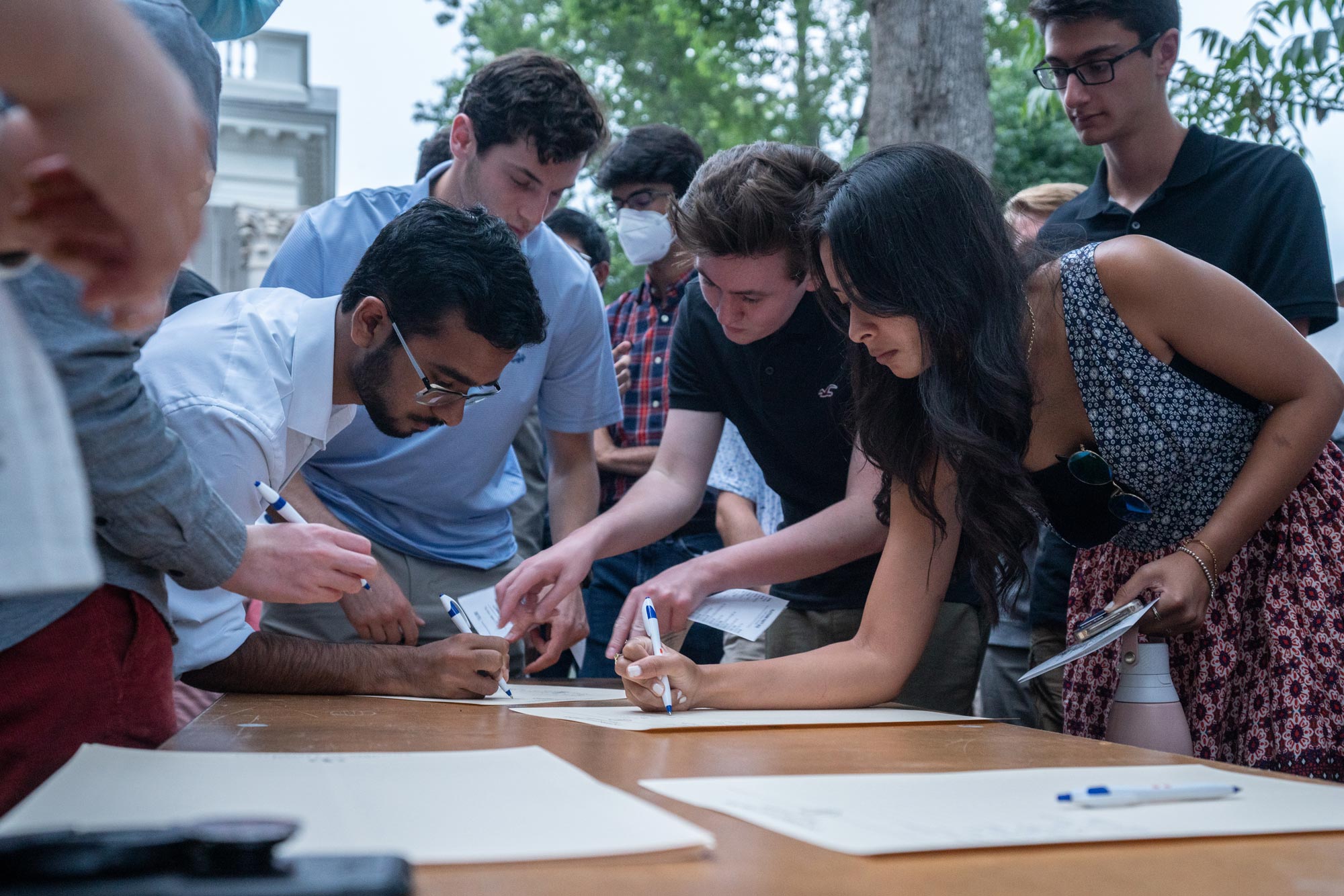 University of Virginia students crowded around a table, signing their names on sheets of paper