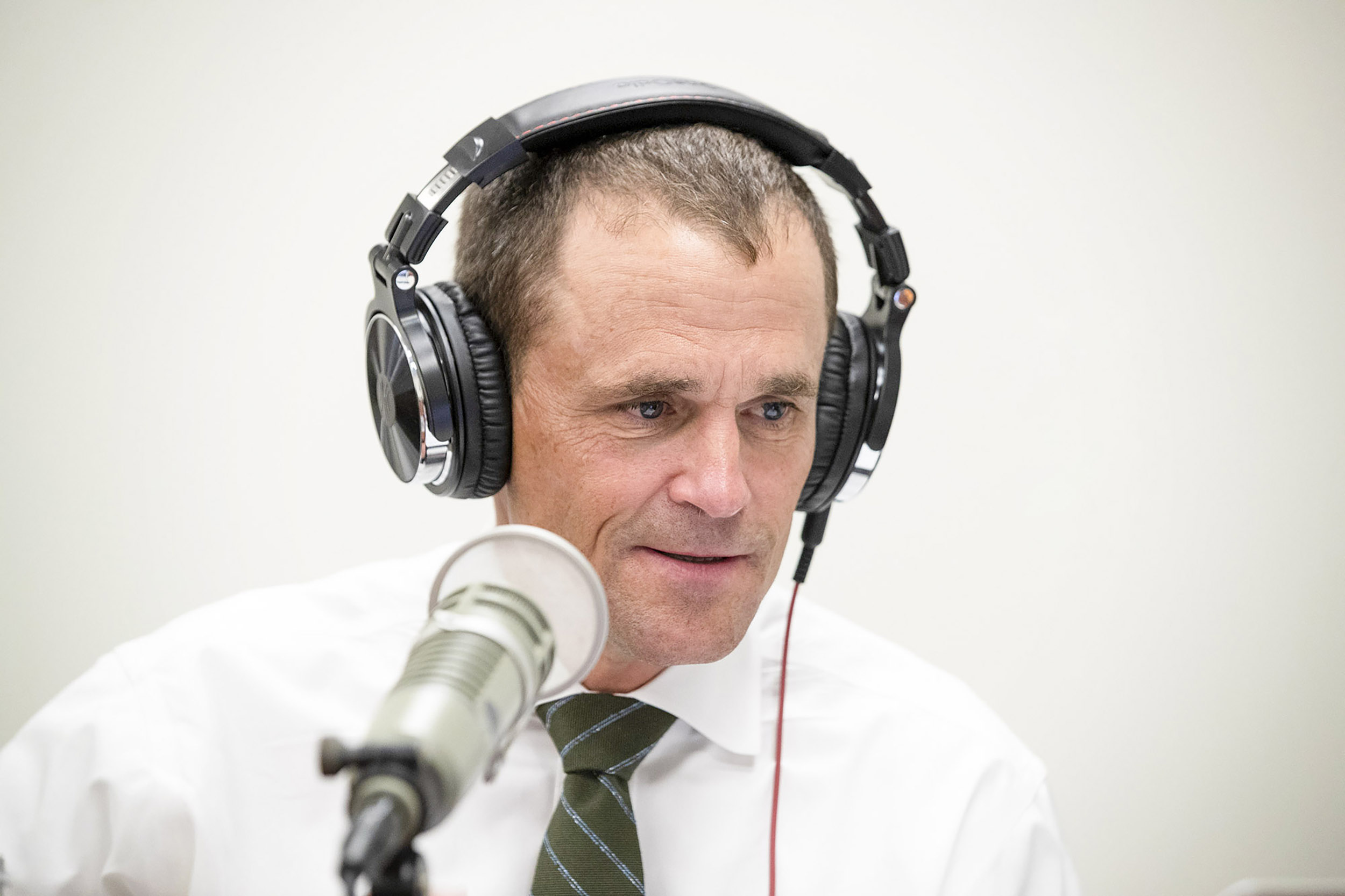 Jim Ryan wears a set of headphones and speaks into a microphone