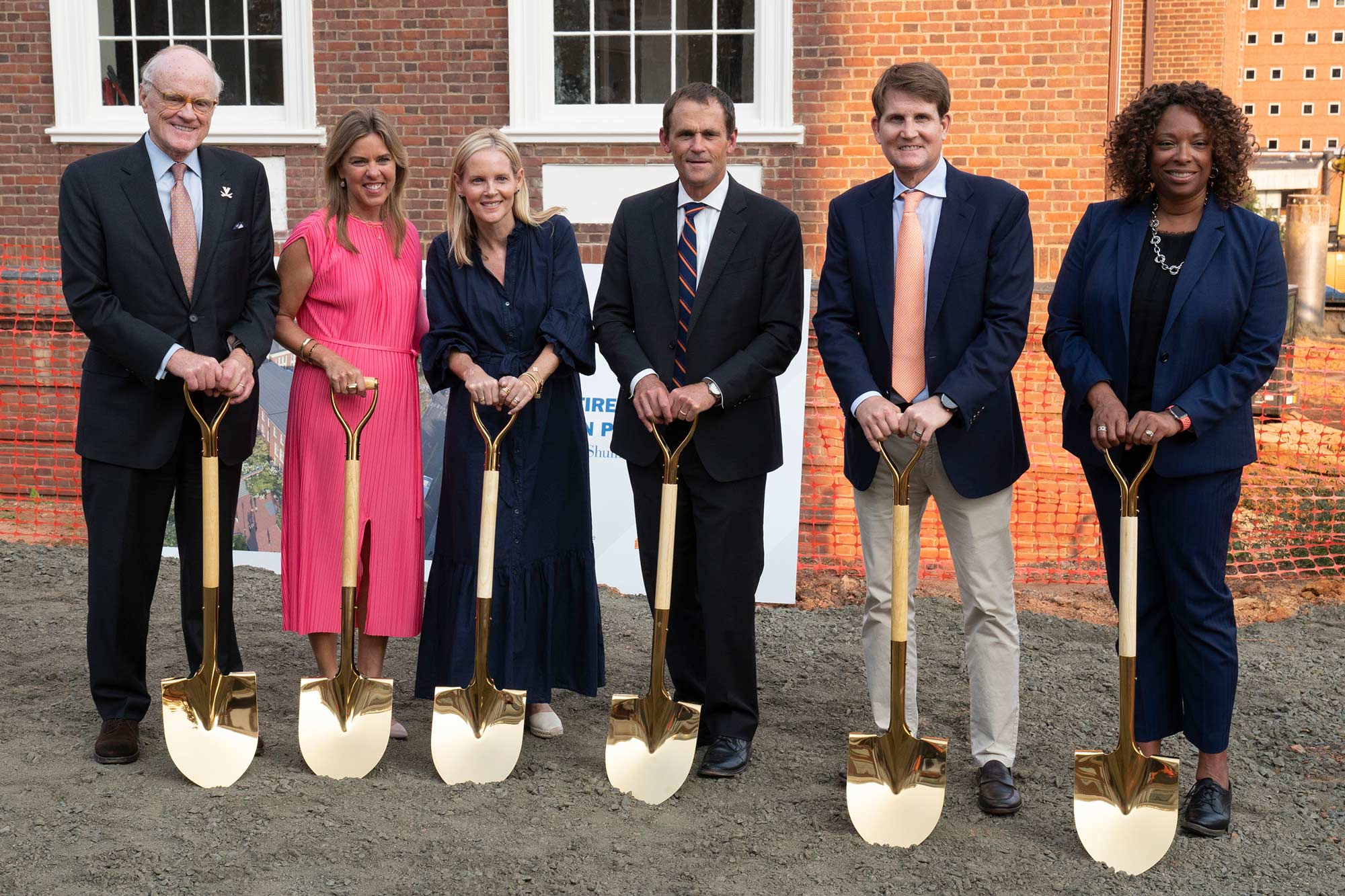 Group of six people with golden shovels in the ground smiling at the camera during a groundbreaking ceremony.