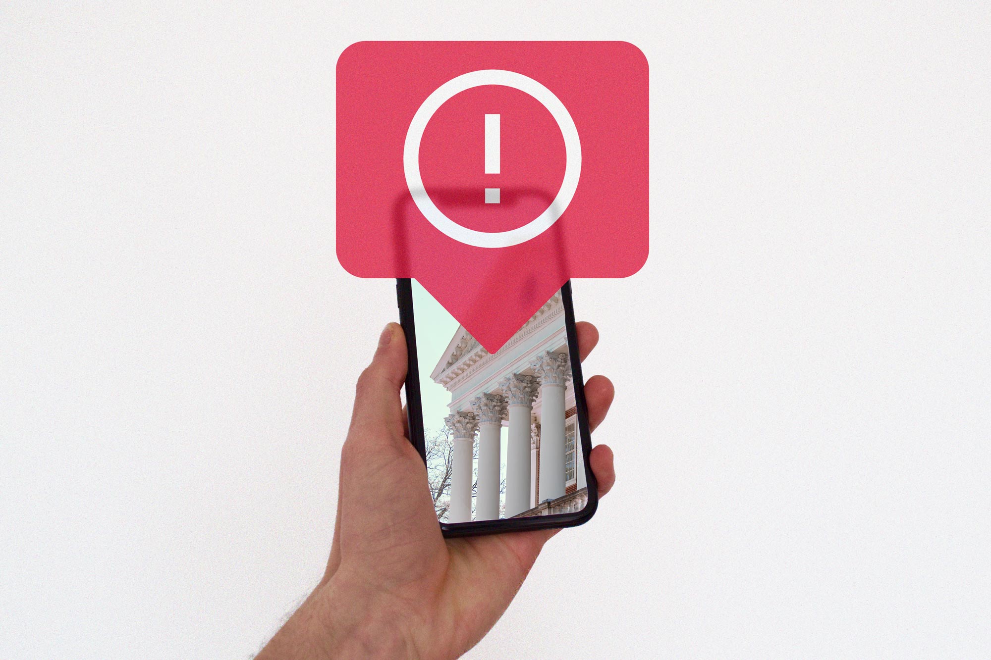 Hand holding phone with a graphic of an alert icon overlayed on the phone