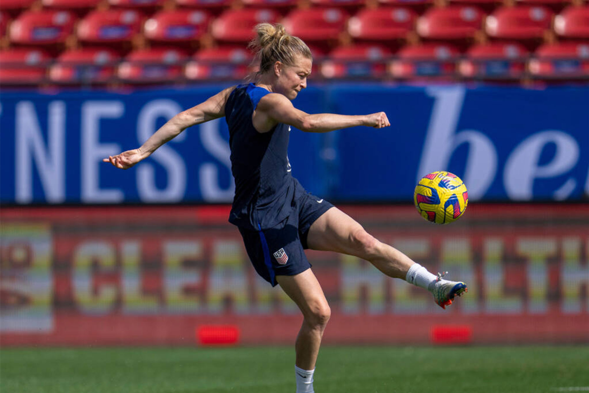 Emily Sonnett about to kick a soccer ball in the air