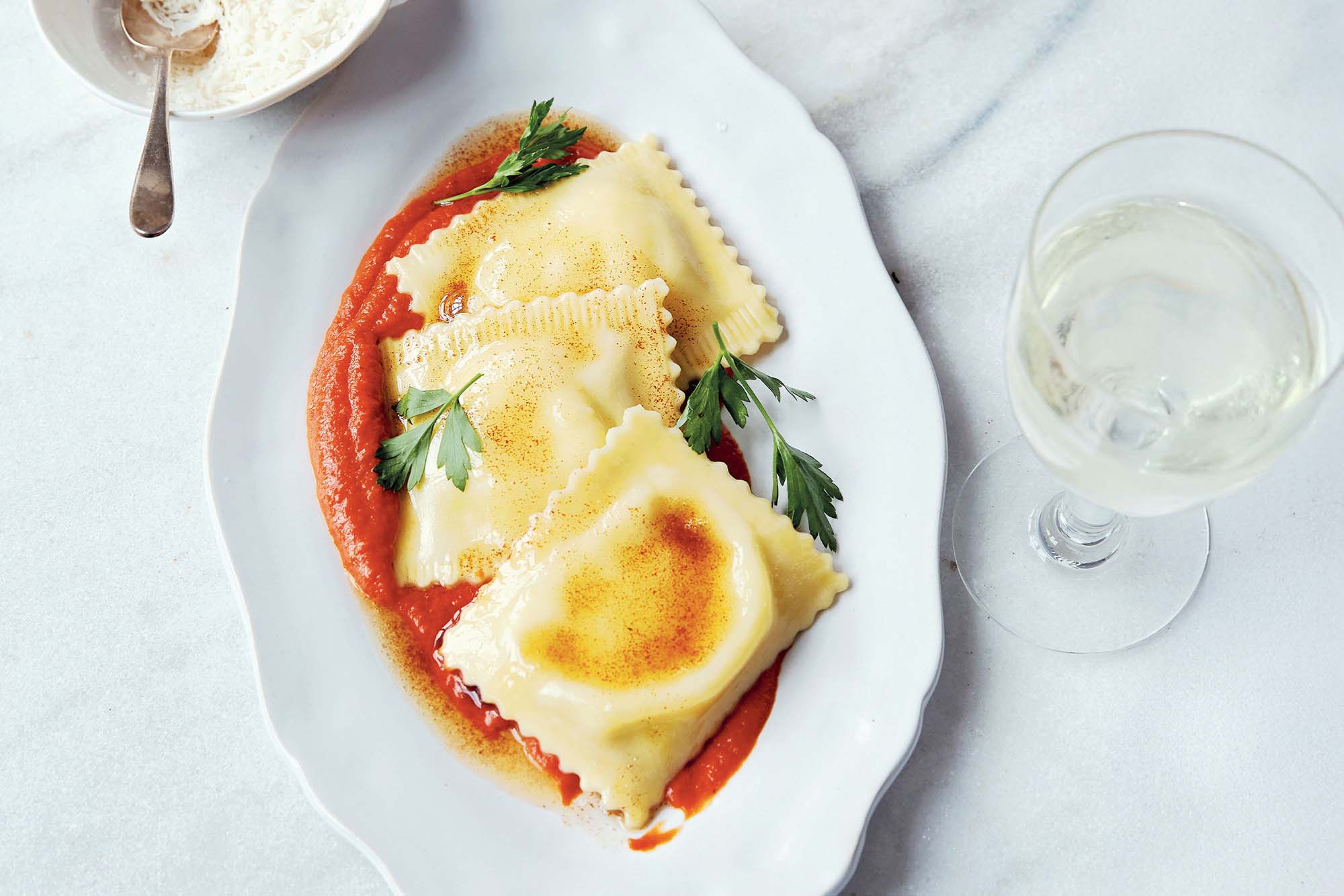 Three large ravioli elegantly plated with red sauce and parsely