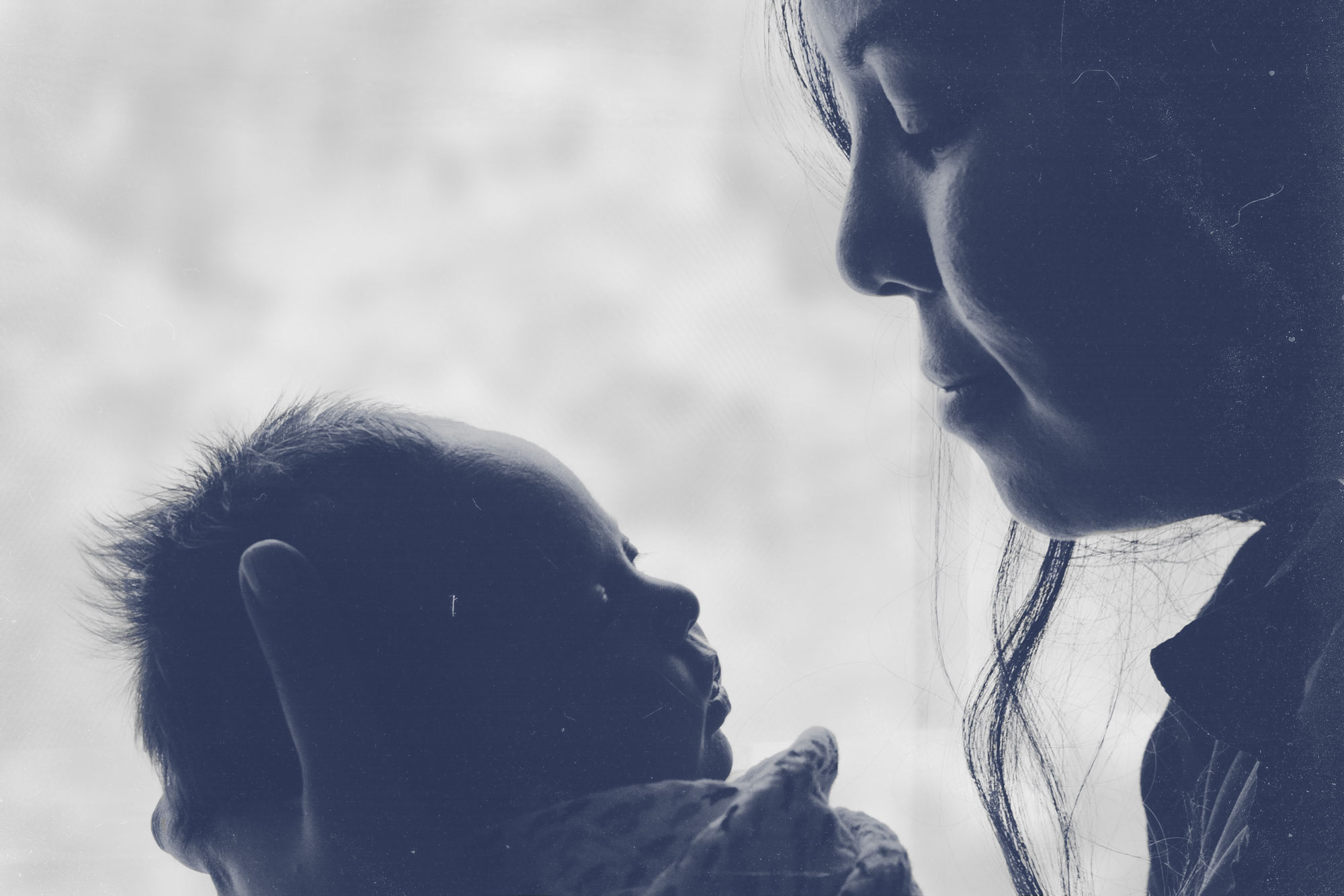 Mother holds her baby with a blue graphic color overlay on the image