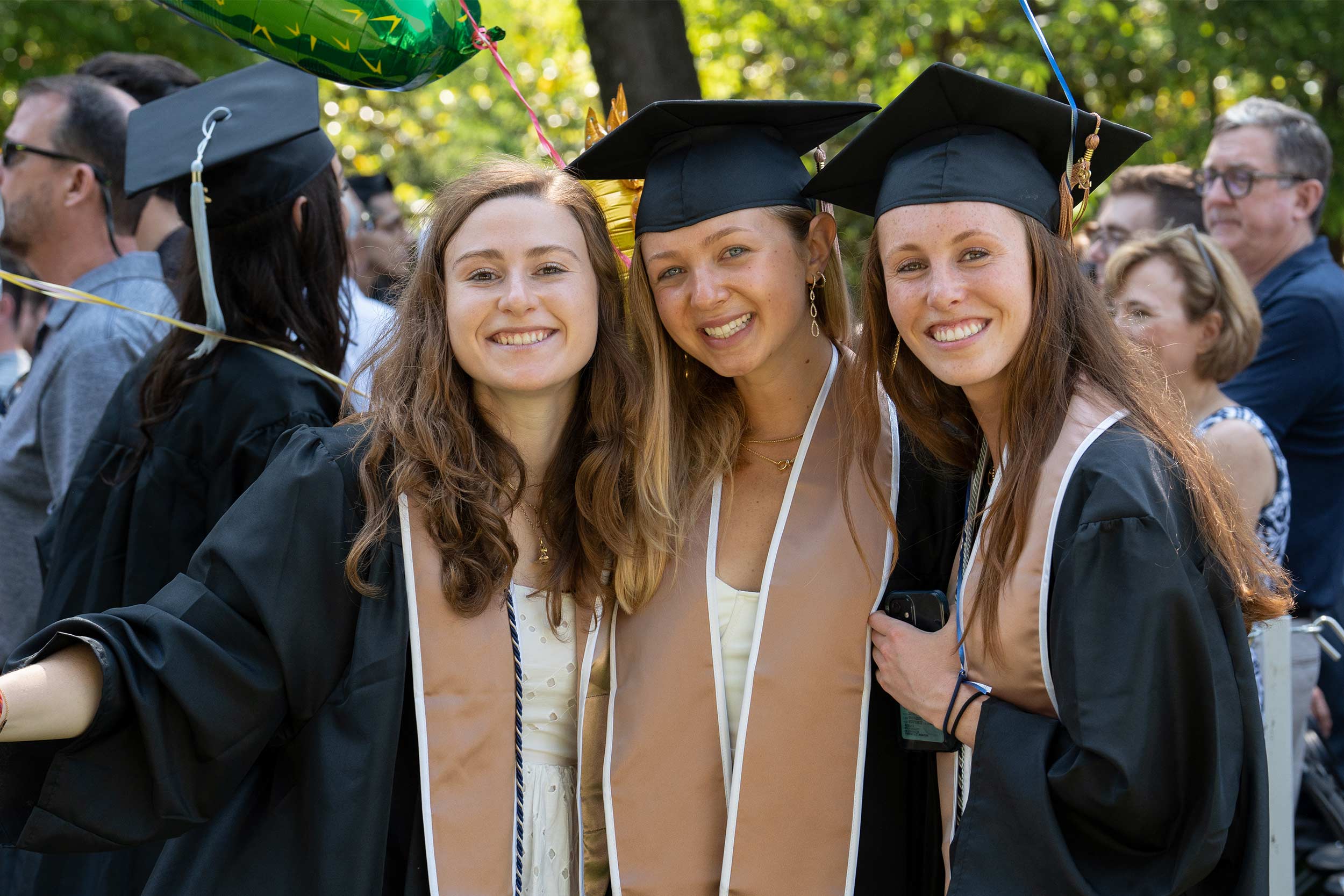 Three female graduates smile for the camera