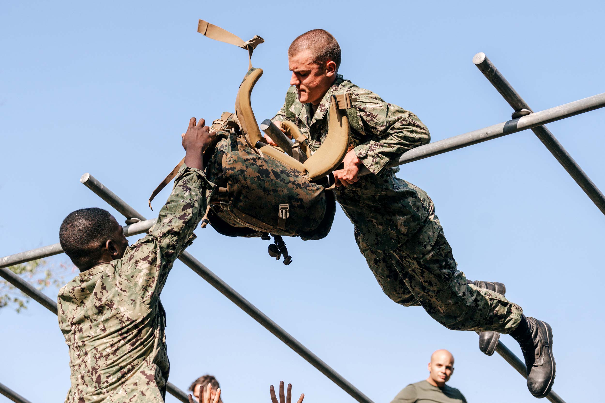 Candid photo of Ouzman Cisse on the left and Henry Addison undergoing military training as they tackle the obstacle course.