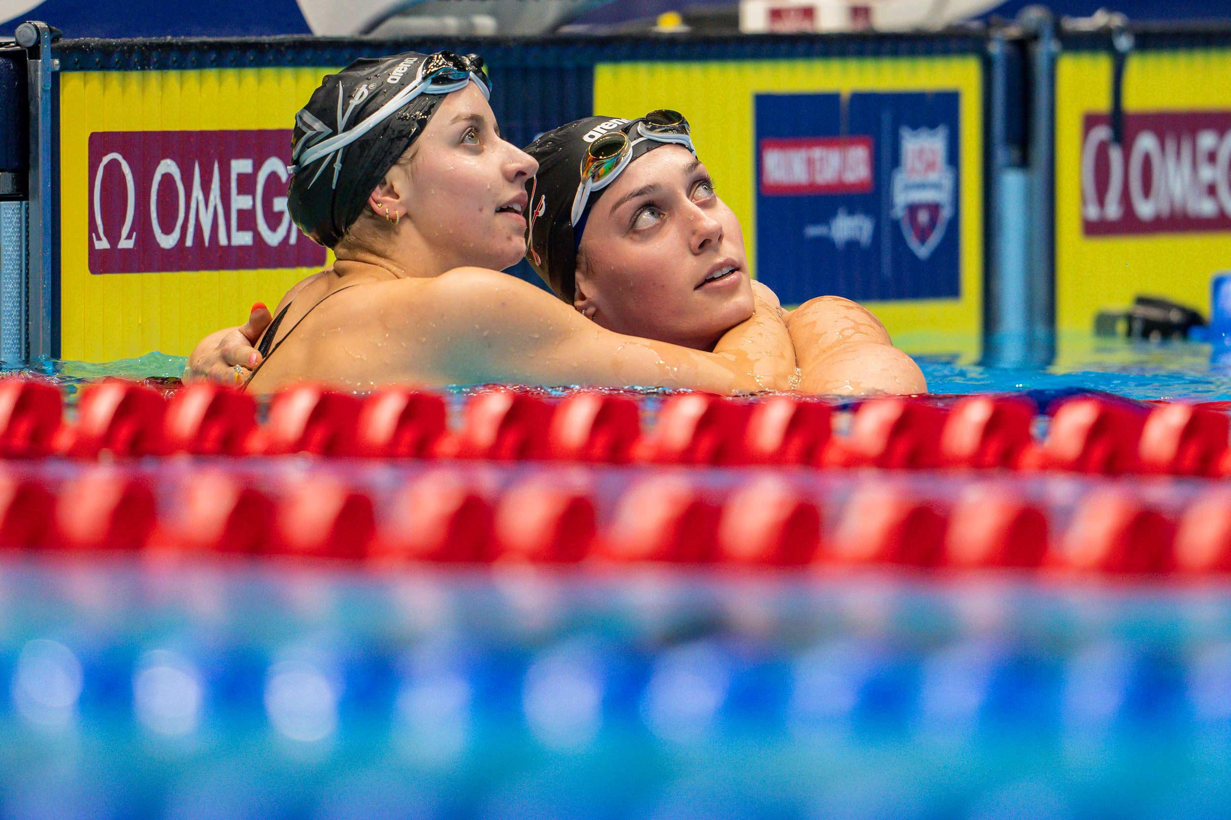 Kate Douglass, left, and Alex Walsh, right, hold each other as they look at the scoreboard waiting for results