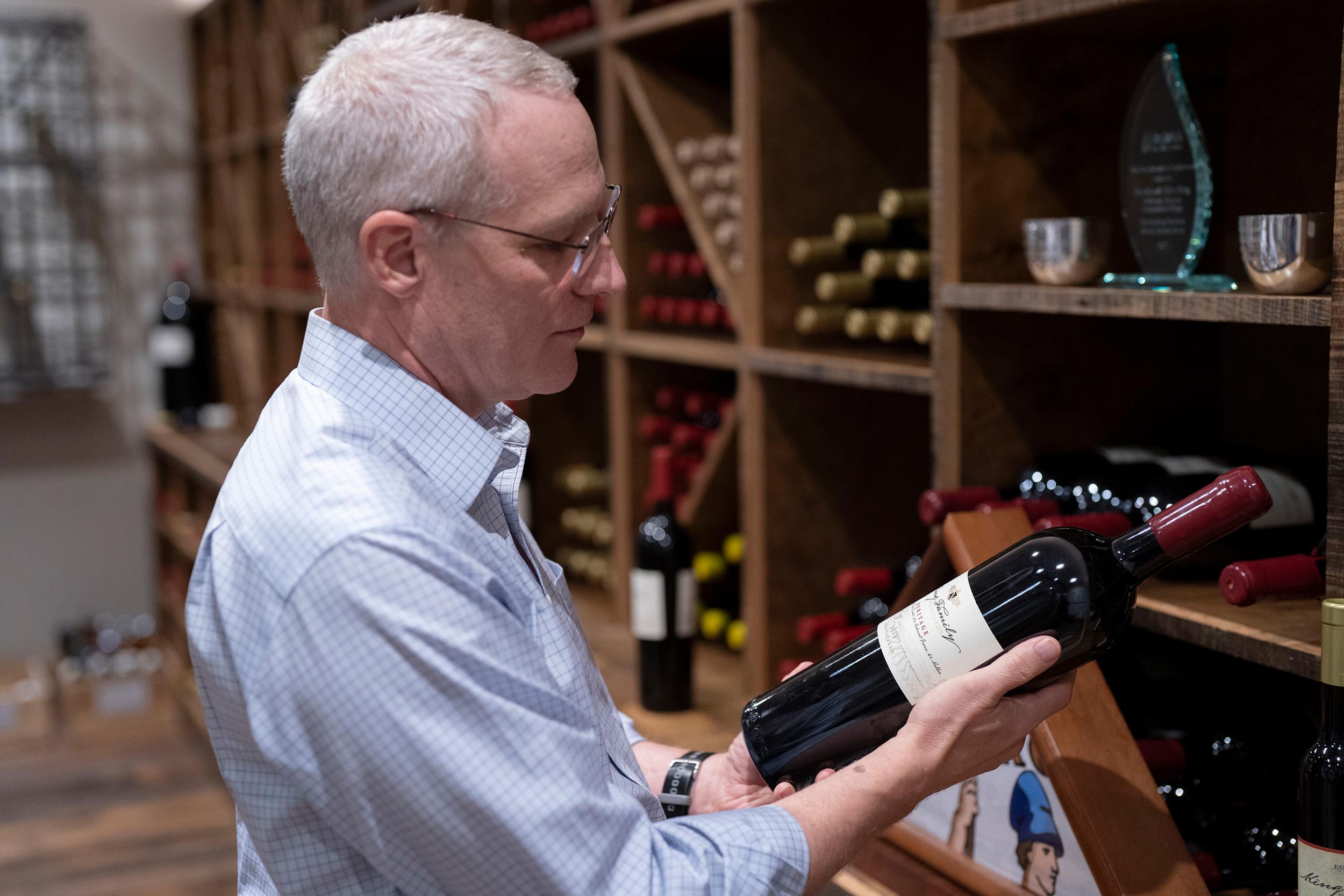 Rodney Sullivan in a wine cellar looking at a bottle of wine
