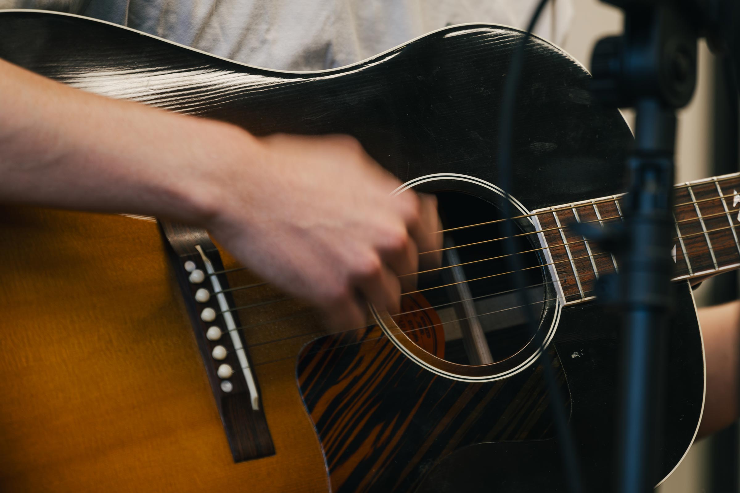 A hand strums on a guitar