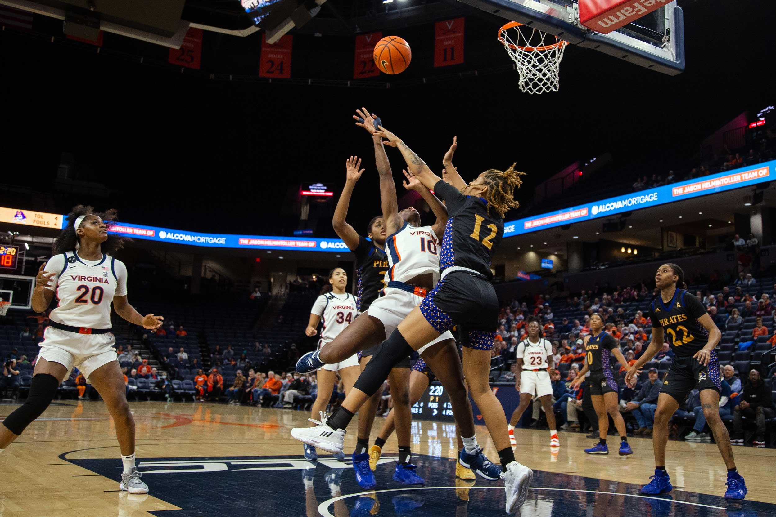 UVA basketball players jumping for the ball against opponents at the net