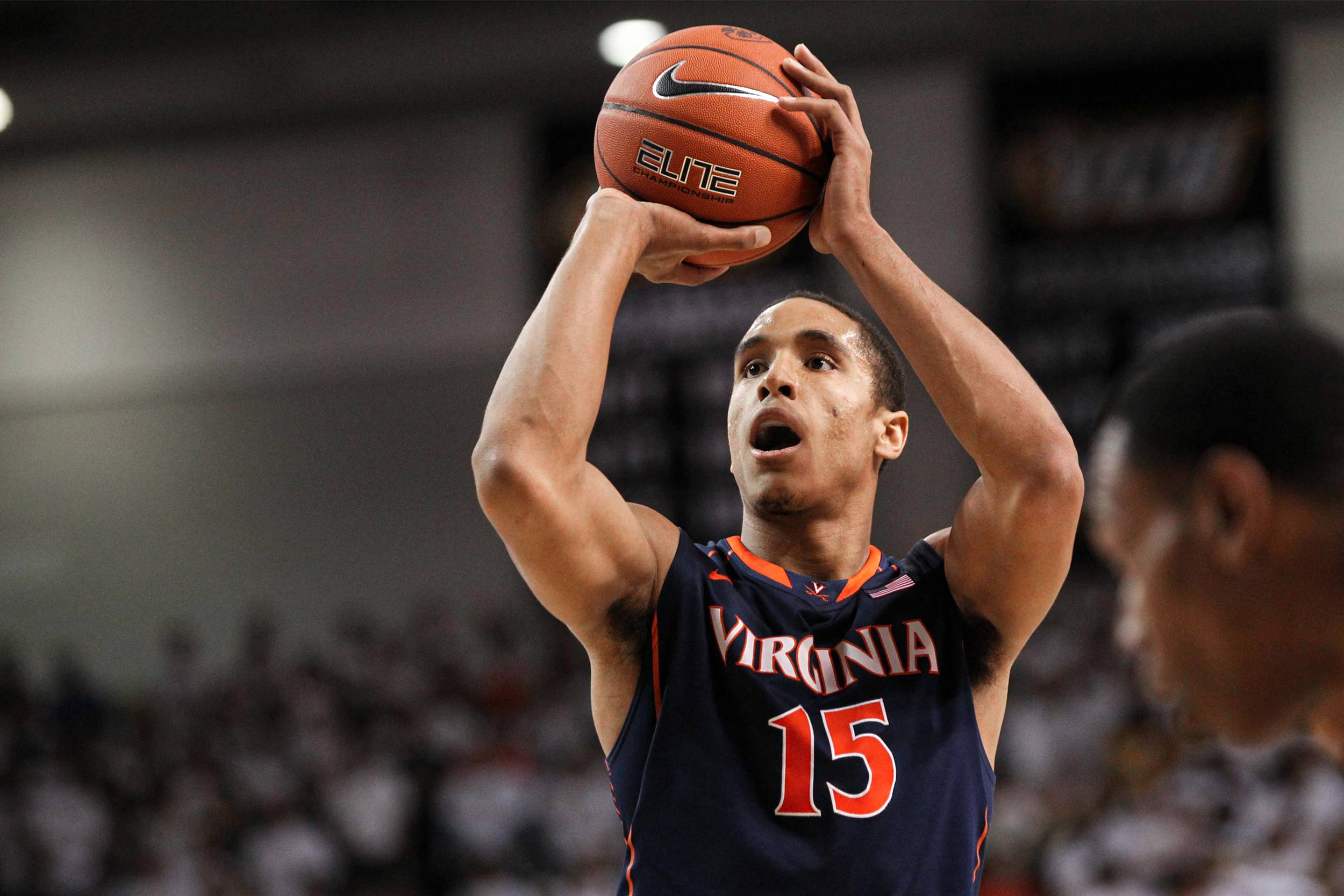 Action shot of Malcolm Brogdon in U V A jersey getting ready to shoot a basket during U V A basketball game