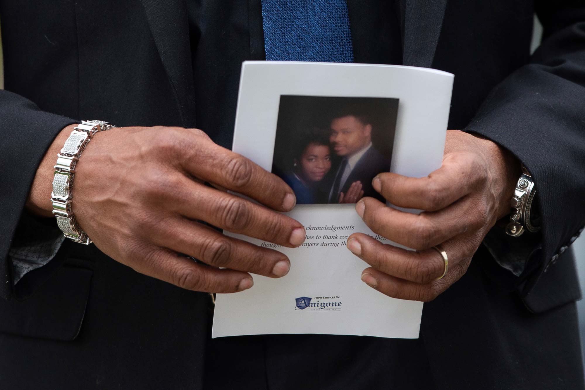 A pair of man's hands holds a memorial program