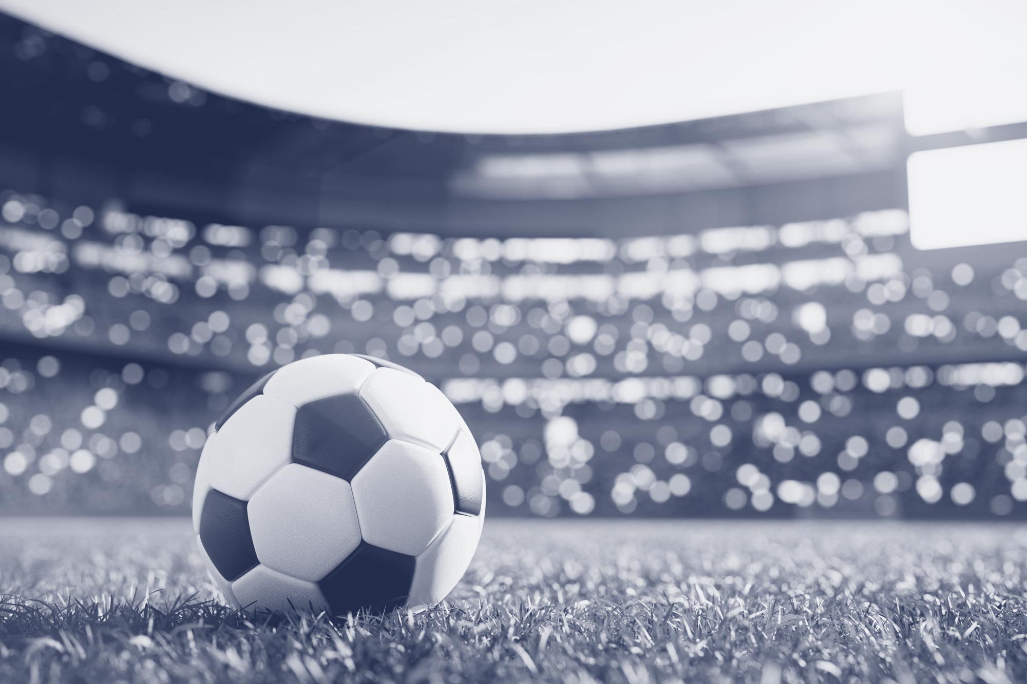 Black and white image of a soccer ball on an empty field in a stadium