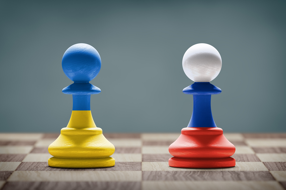 Chess pieces on a chess board.  left chess piece is Blue on top and yellow on the bottom representing Ukraine and the right chess piece is white, blue, then red, representing Russia