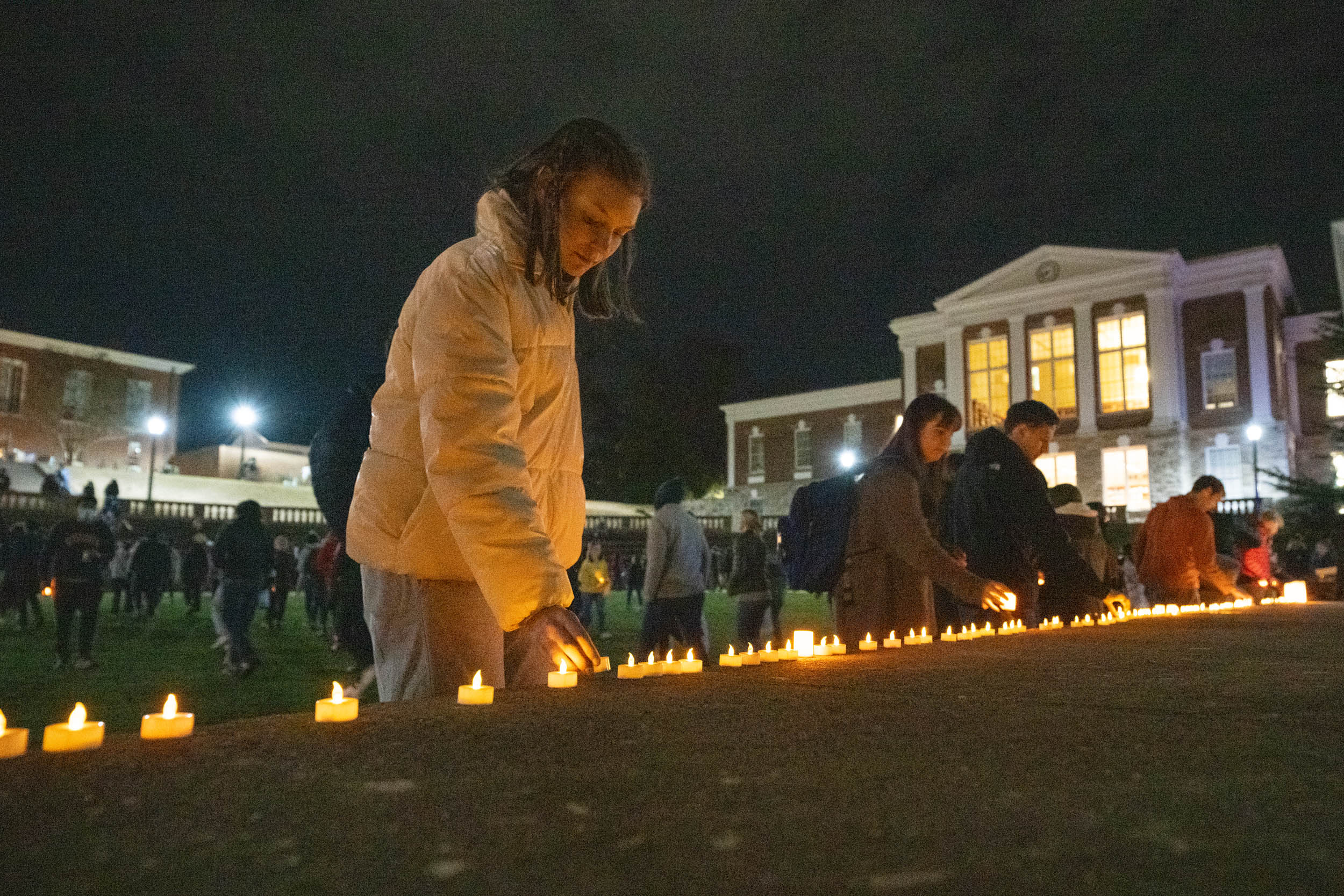 Students ligthing candles at a vigil for Ukraine.