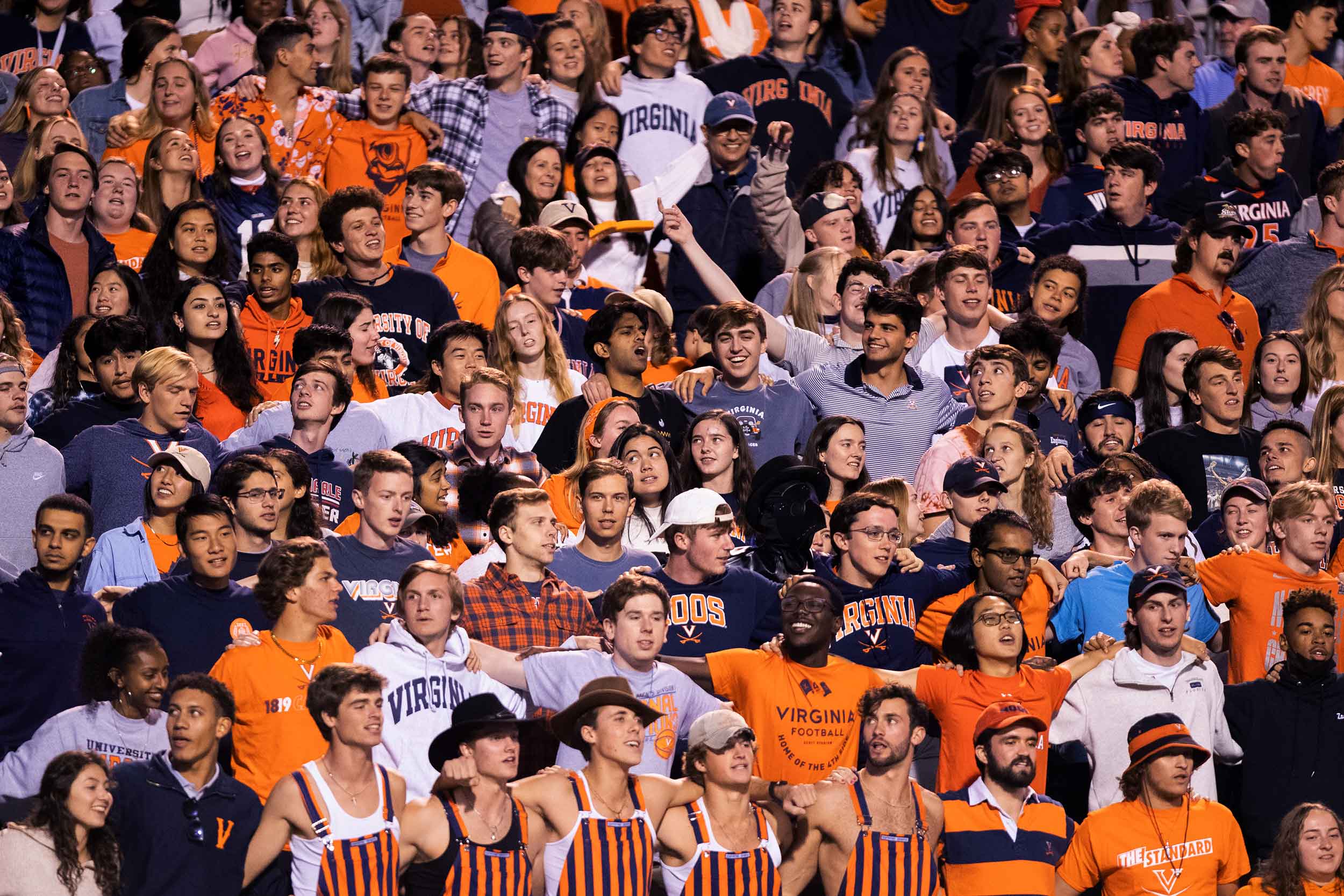 A crowd shot of students in orange and blue at a home football game.