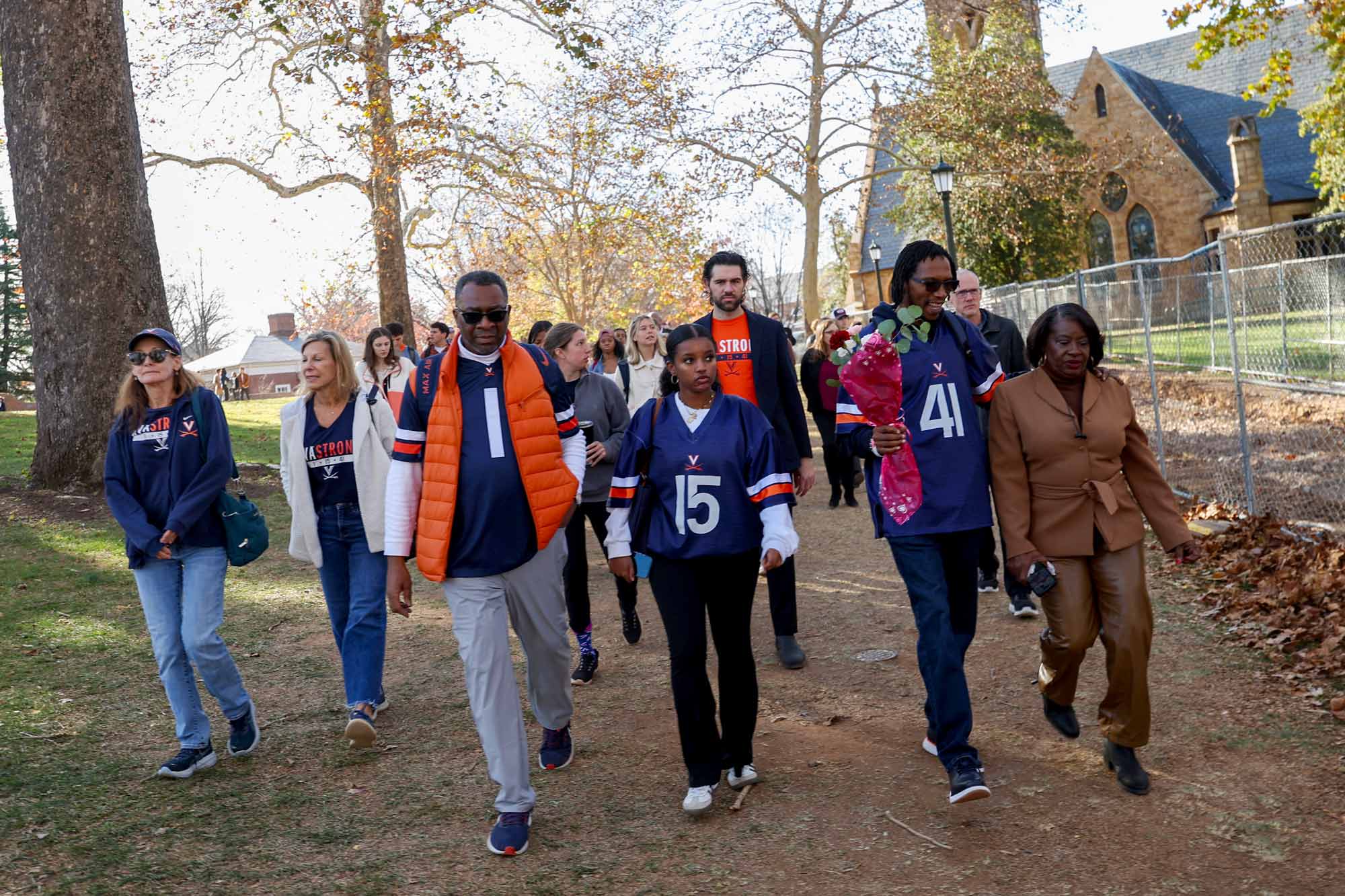 a group of people dressed in UVA football merchandise walking past the UVA Chapel