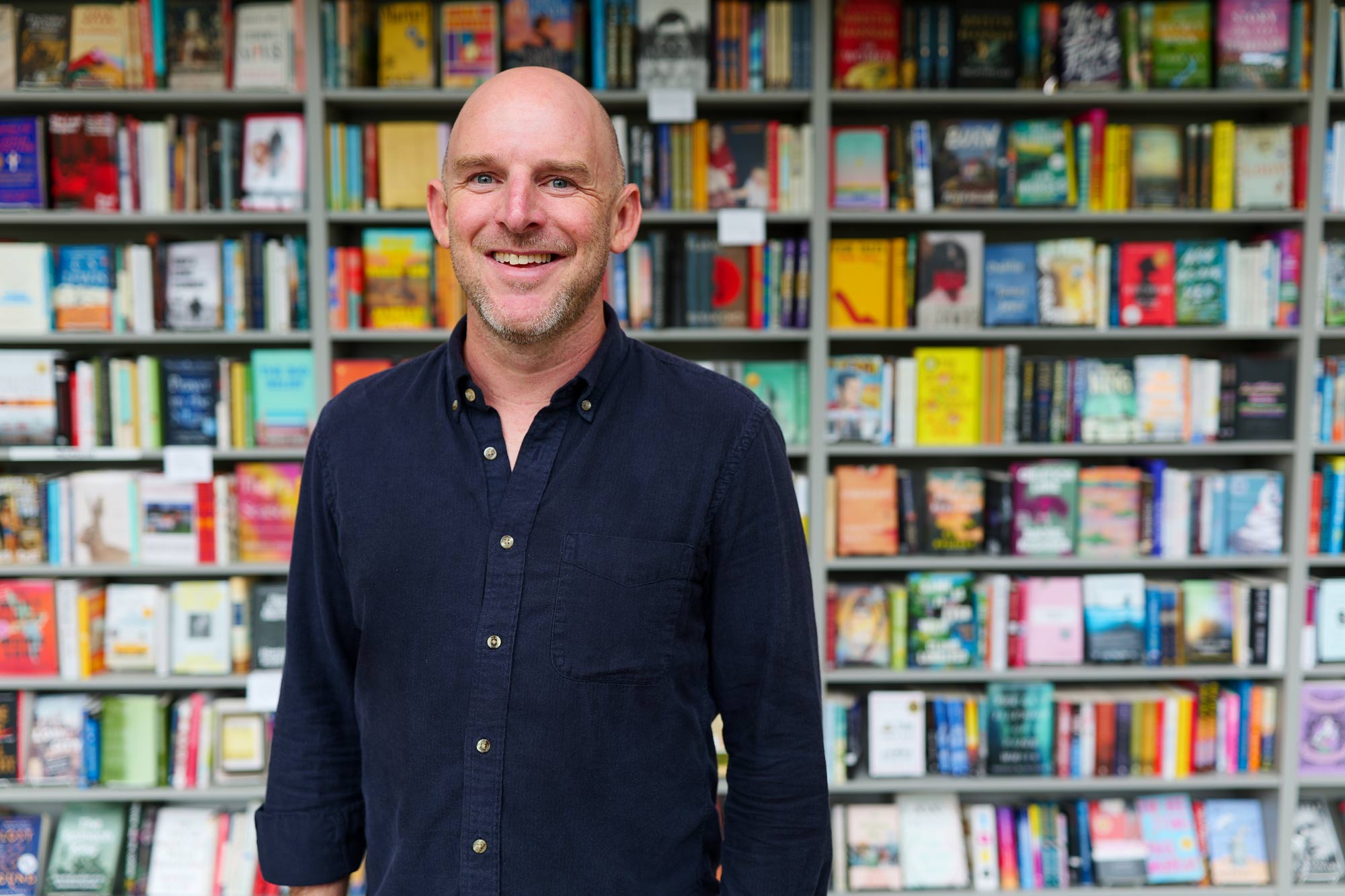 Philip Lorish poses in front of several bookcases in Commerce Street Books