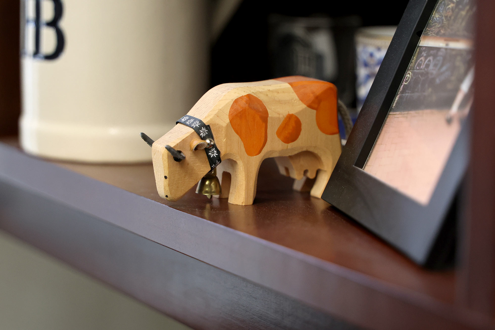 A close up of a wooden cow on a shelf 