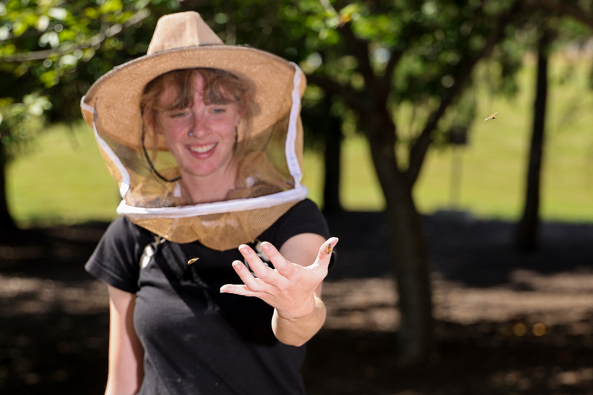 Claire Sherwood weating a protective mask and holding some bees