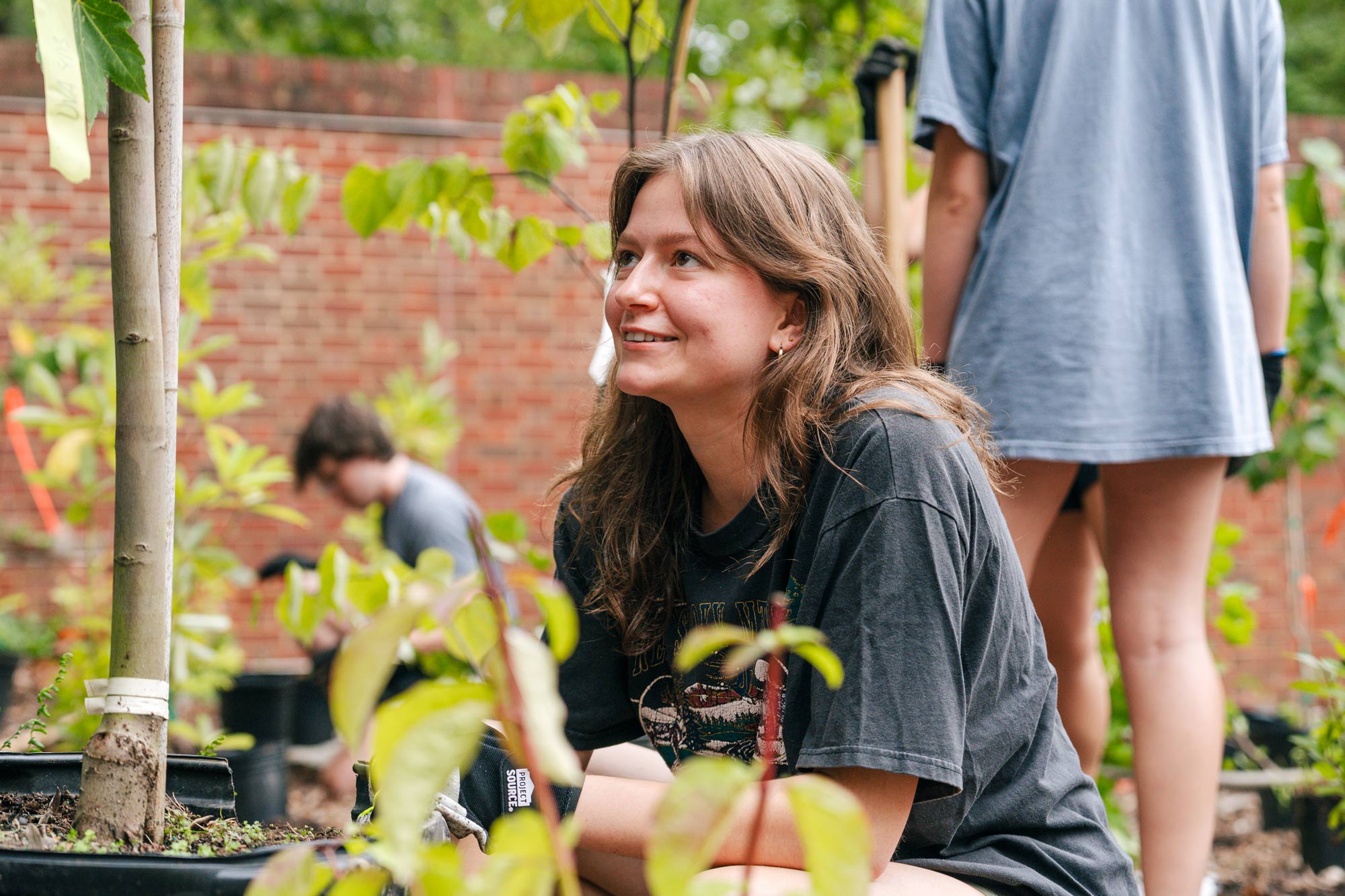 A student gazes up while crouched among plants