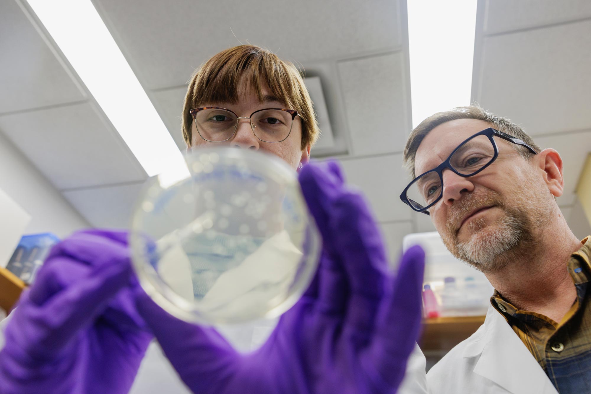 Emily Baum and Tom Baker working with a petri dish