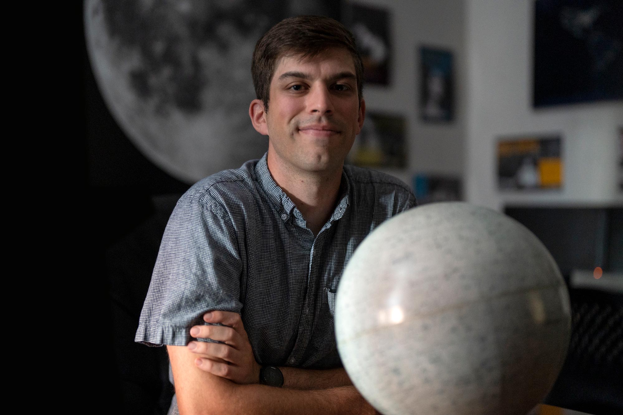 Portrait of UVA astronomer Matt Pryal with a globe in front of him