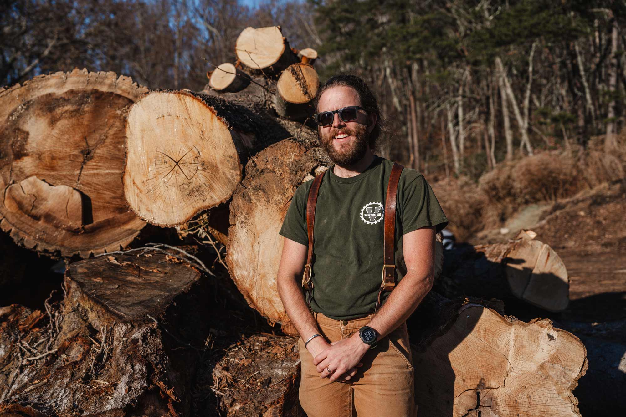 Andrew Spears, co-founder of UVA Sawmilling, stands next to a pile of logs felled at the University Gardens apartments site. 