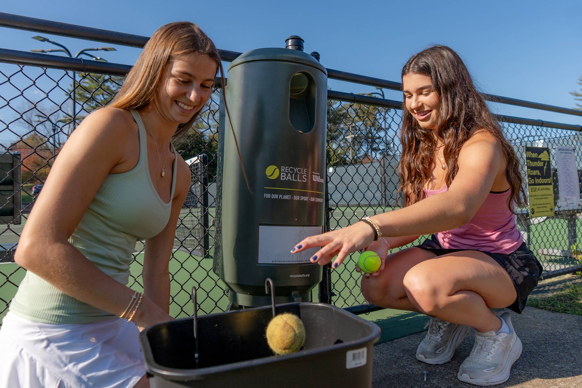 Ava and Emily Samay crouching in a tennis court