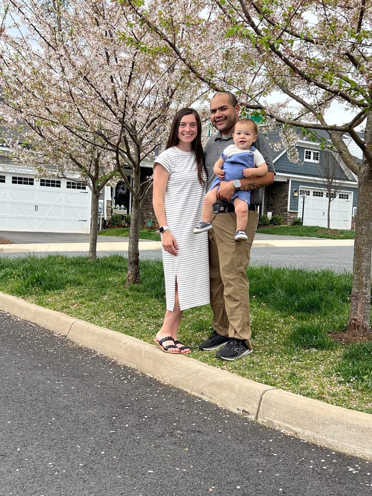 Portrait of U.S. Army Capt. E.J. Rauch poses with his wife and son outside their home.