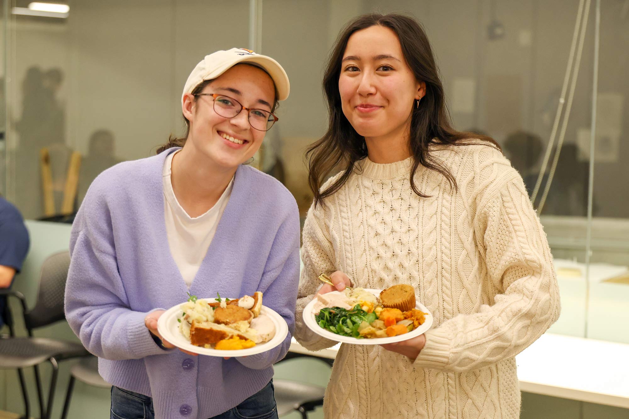 Portrait of Leah Withers, left, and Mai Friedman, fourth-year students, holding plates of food.