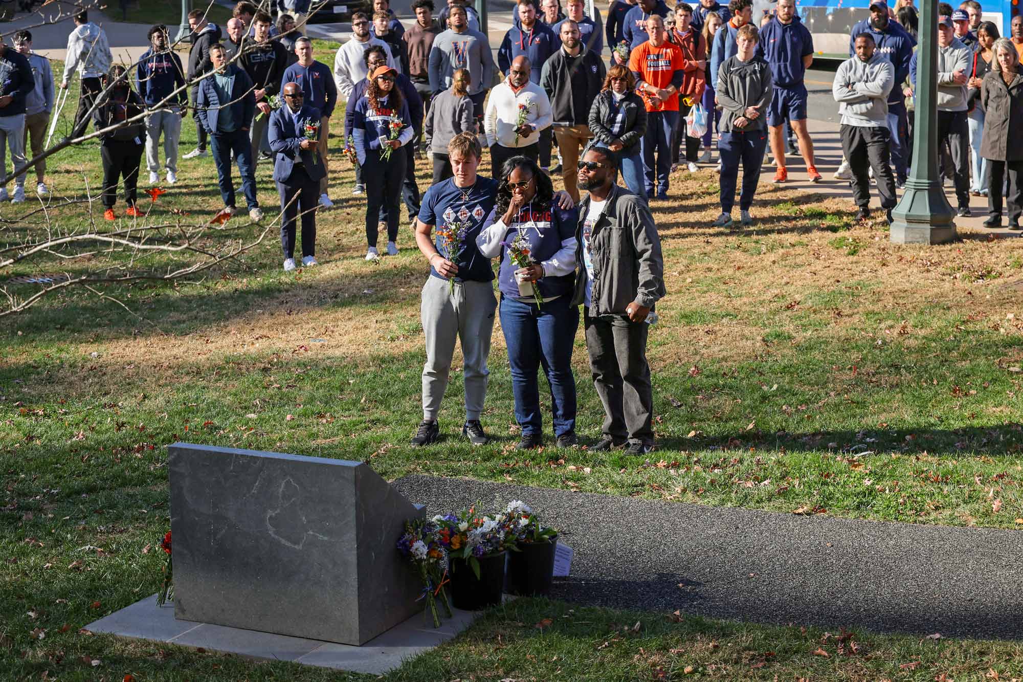 Will Bettridge and Michael Hollins Jr. console Happy Perry at the UVA memorial service in front of a crowd of attendees.