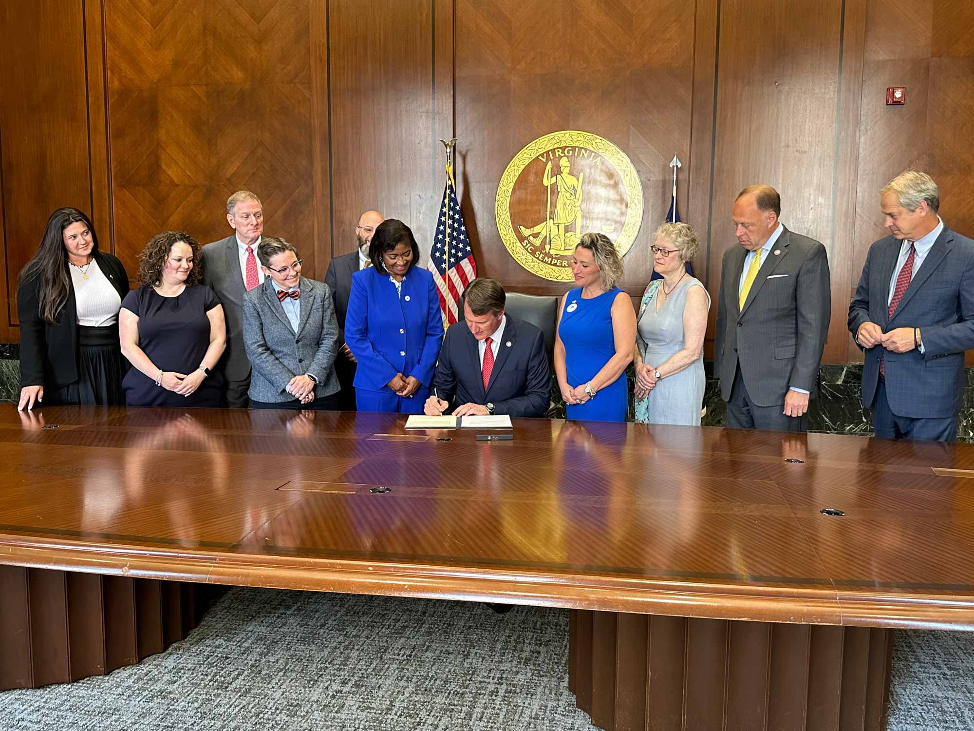 Apple and her colleagues watch Virginia Gov. Glenn Youngkin sign legislation 