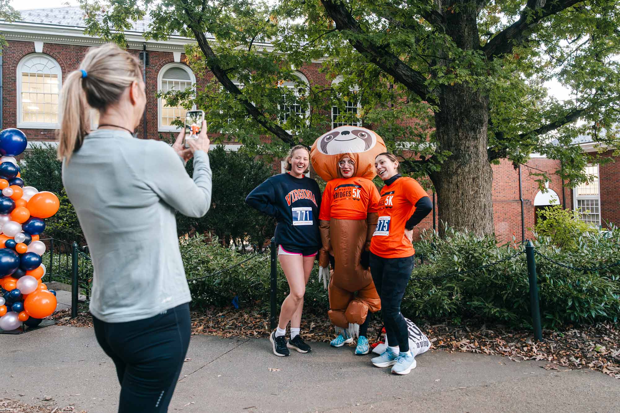 Three people gather for a photo as another person takes their picture on a phone