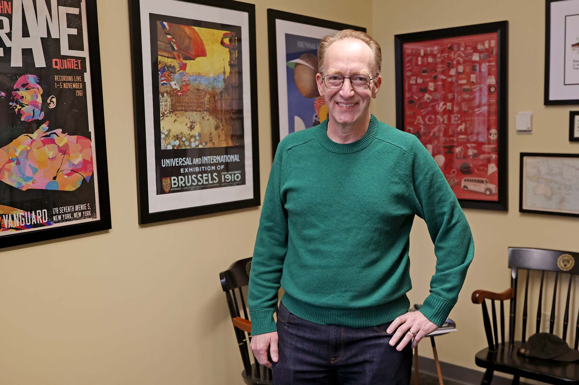 Gallmeyer poses in front of posters hanginig in his office