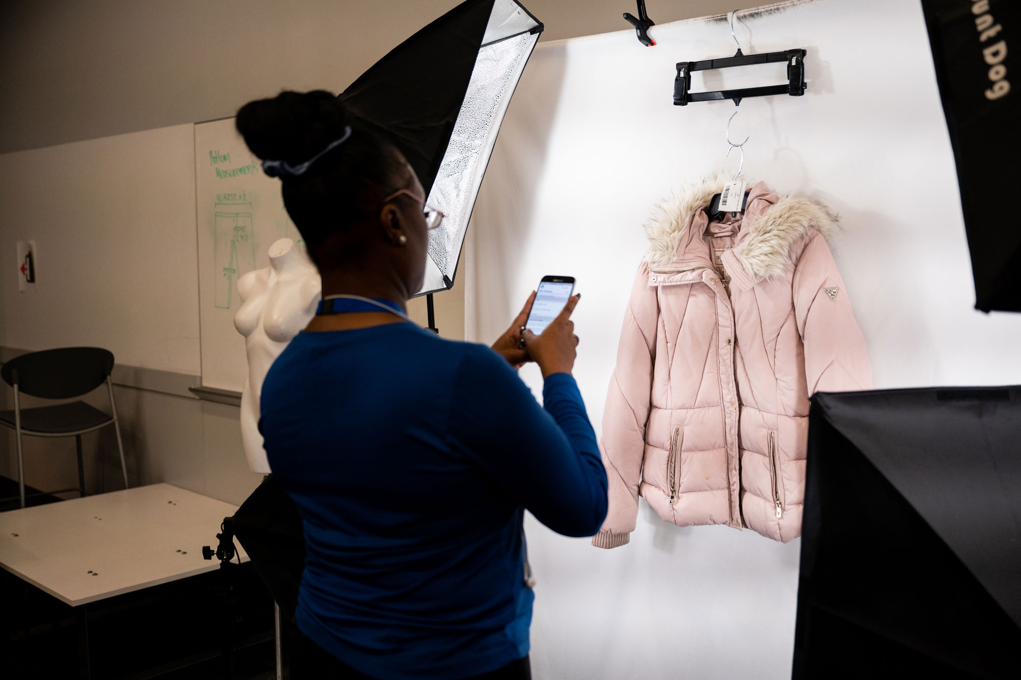 Employee photographing a pink coat on a white background to include online