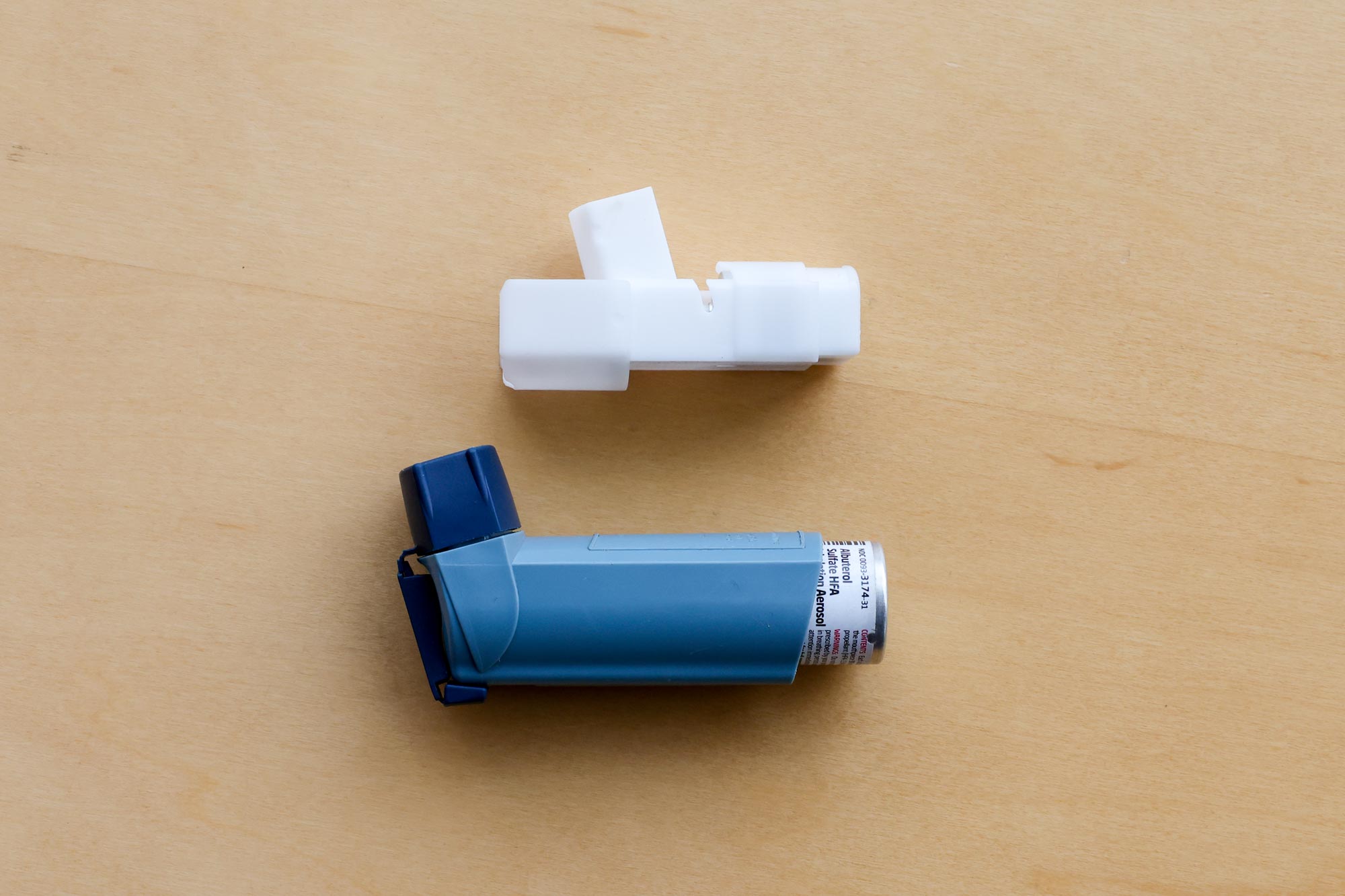 Lanham's device prototype next to a standard inhaler showing the innovation in size and wearability.