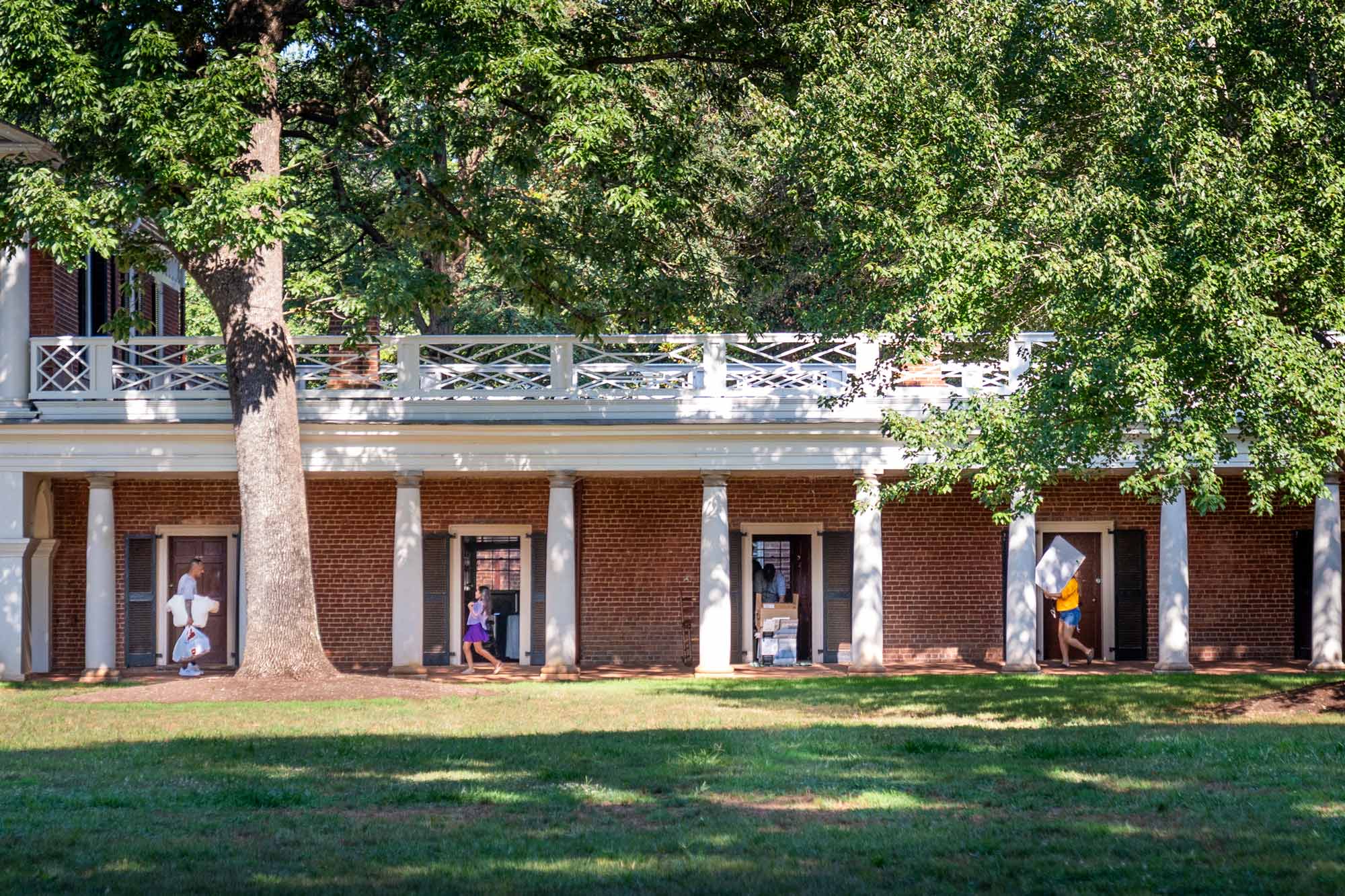 four people conversing in the doorways of their Lawn rooms at UVA