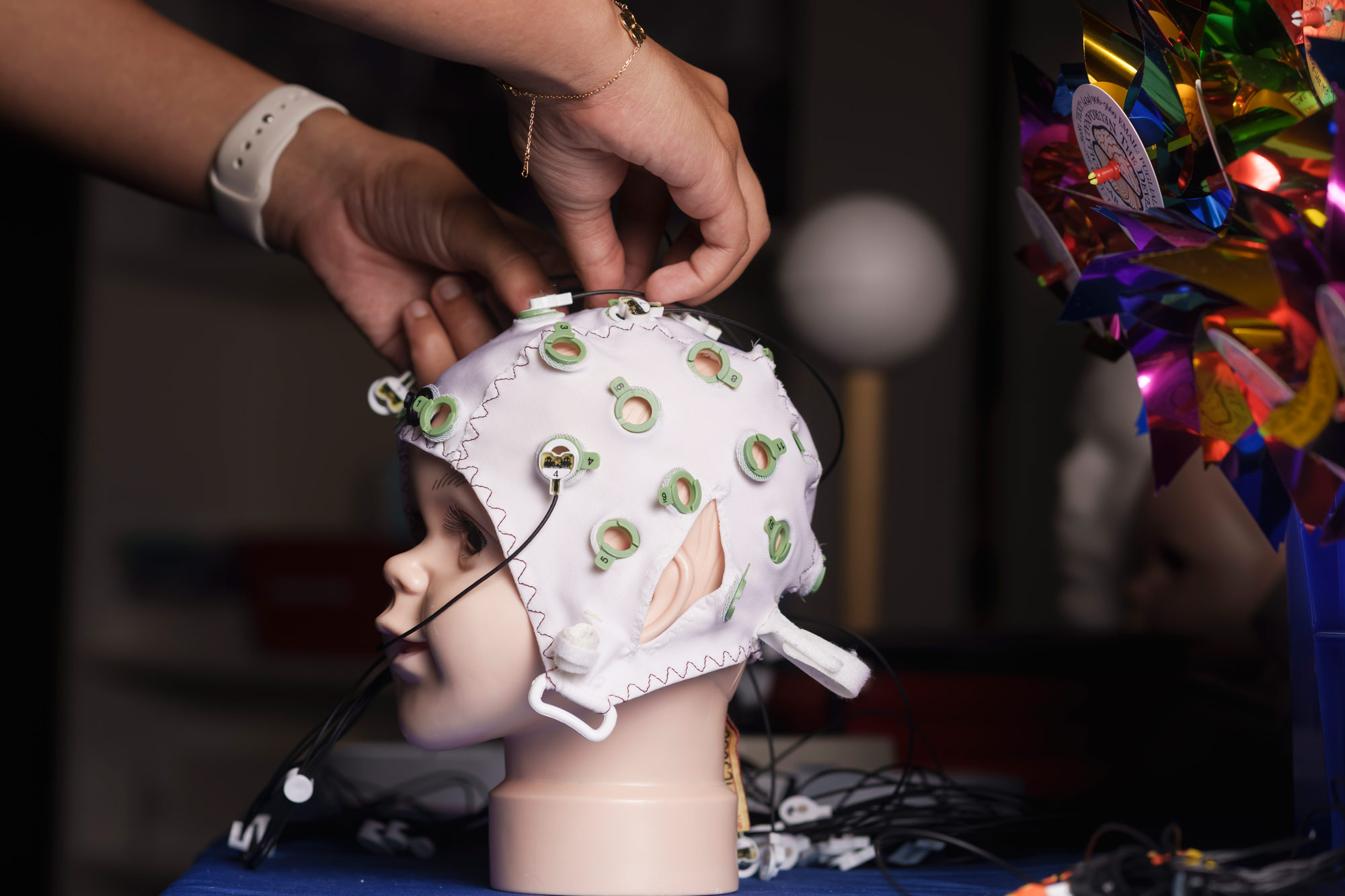 hands placing sensors in a brainwave monitoring cap on a medical mannequin