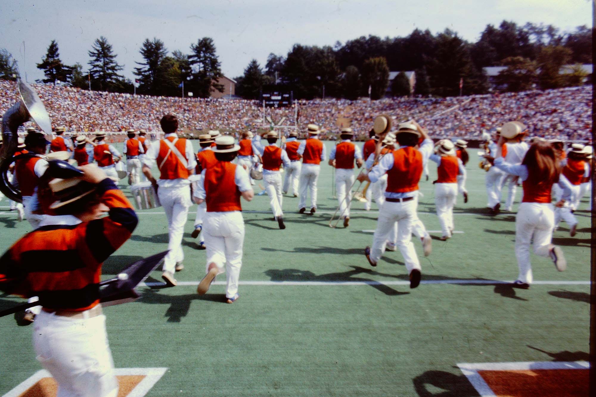 still image from the film “Pep Banned” of the musical group running onto the UVA field during a performance.