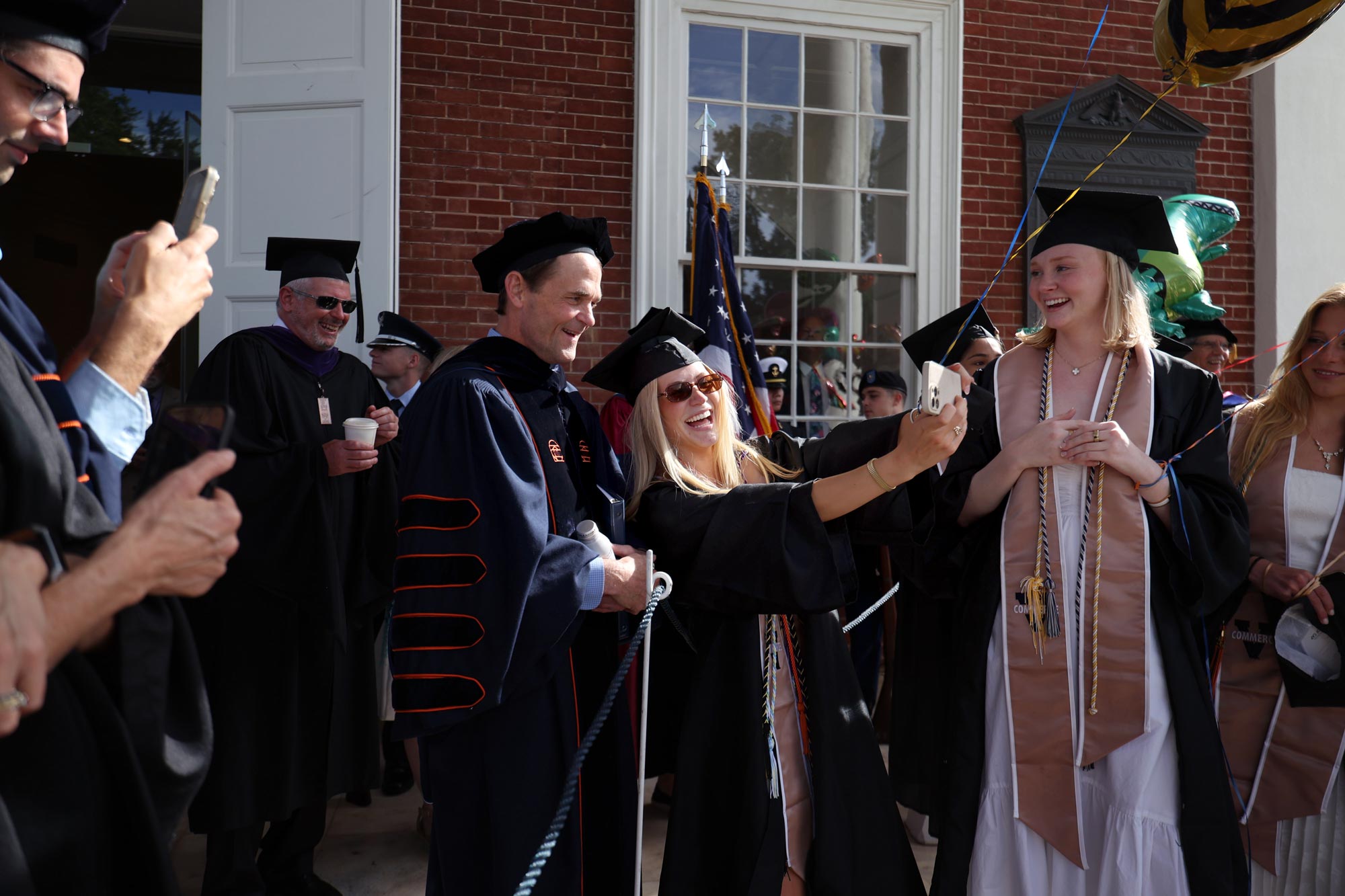 UVA President Jim Ryan poses for a selfie with grauating students on the protico of the Rotunda