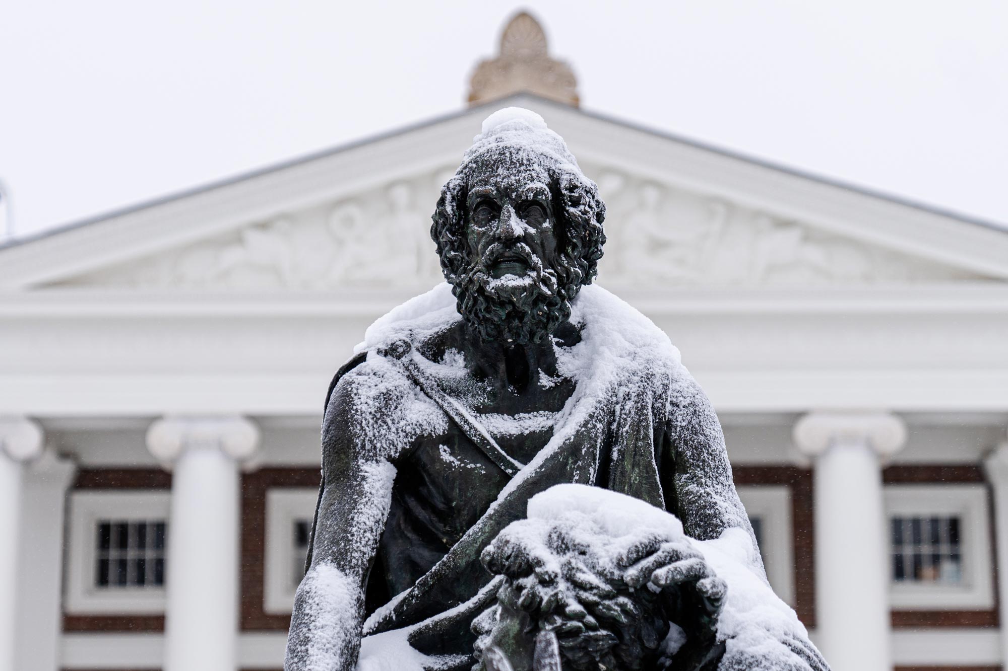 A close up of the Homer statue with snow on his head