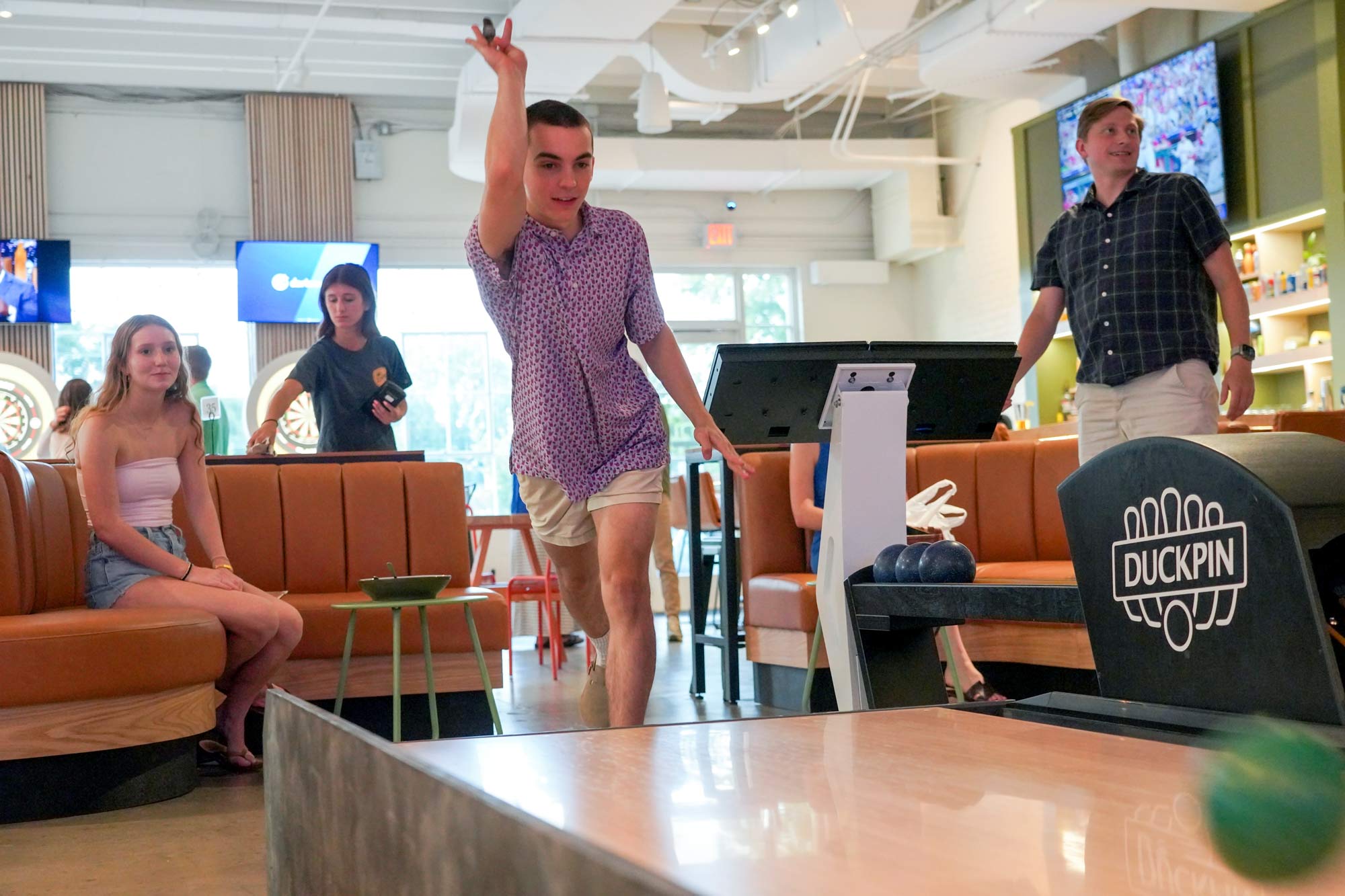 Portrait of person throwing a Duckpin bowling and other watching.