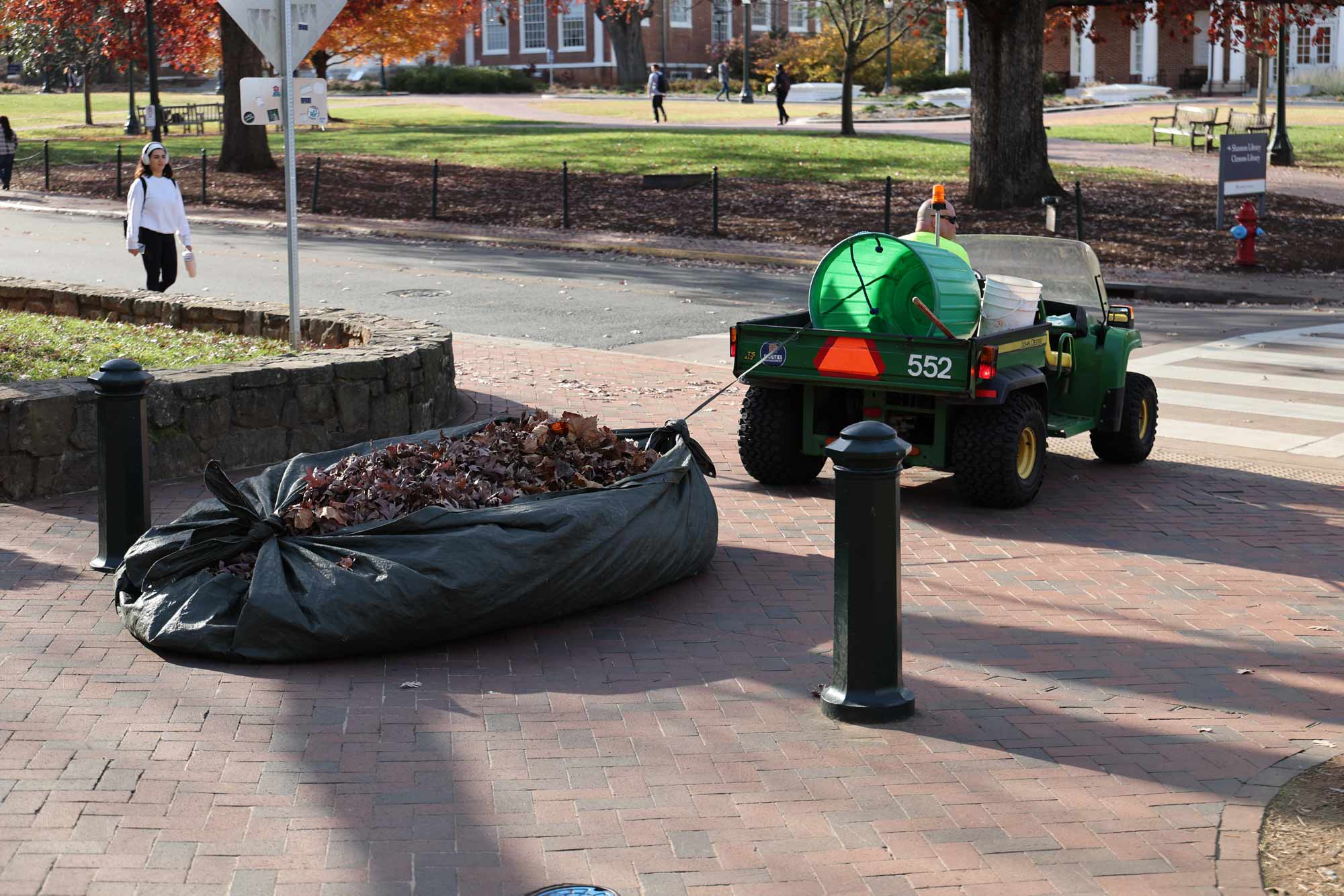 Facilities management hauling leaves in a big black bag