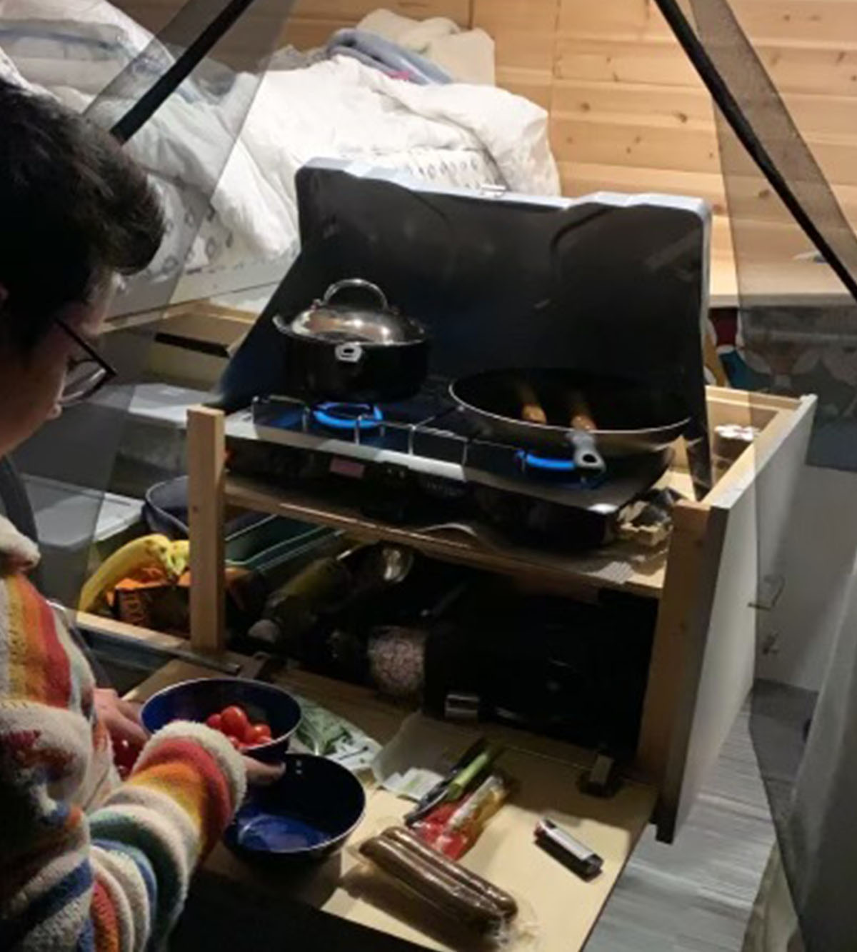 Novak cooking on a camping stove in a travel van.