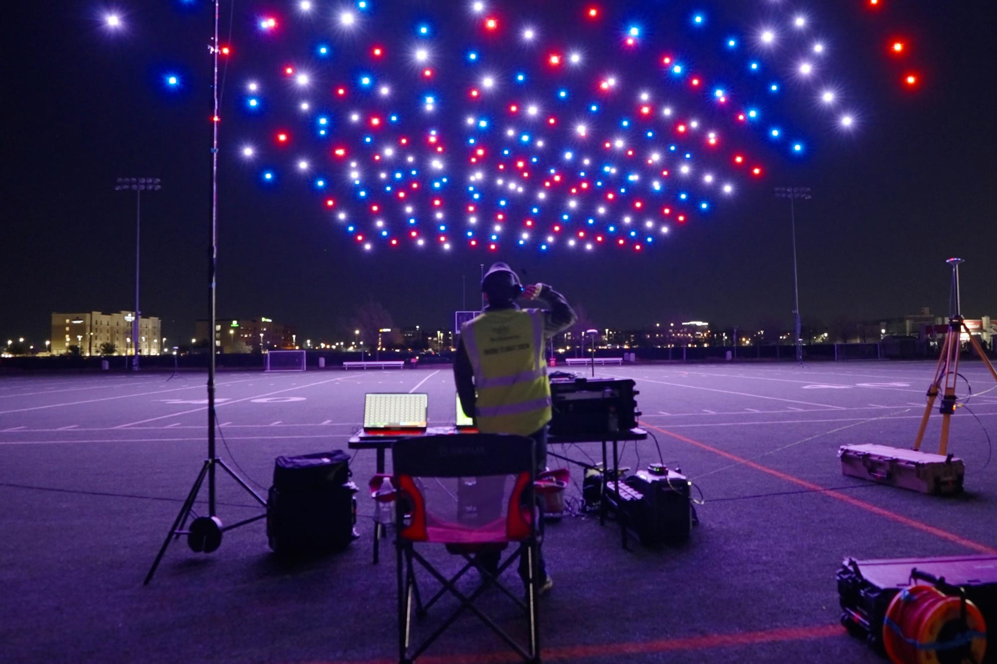 A drone pilot coordinating a drone show at night