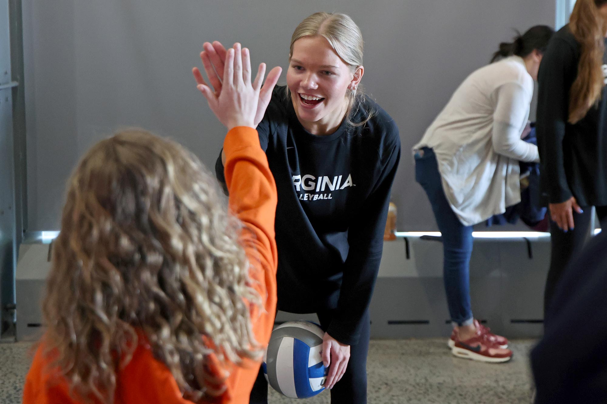 A setter on the UVA volleyball team, freshman Zoey Dood, congratulates a young fan after teaching her some basic skills of volleyball