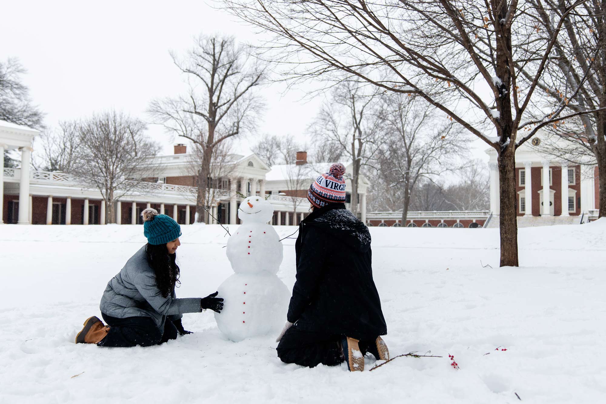 Two students building a snowman on the Lawn