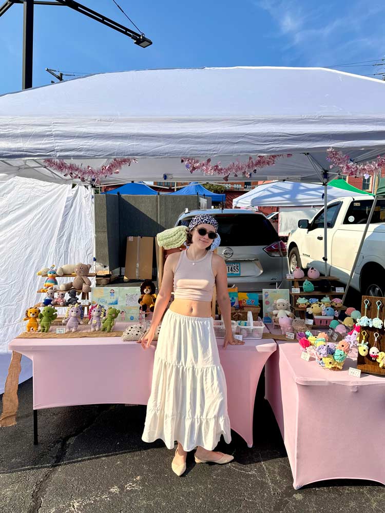 Portrait of Polina Andreeva selling crochet toys at the city market.