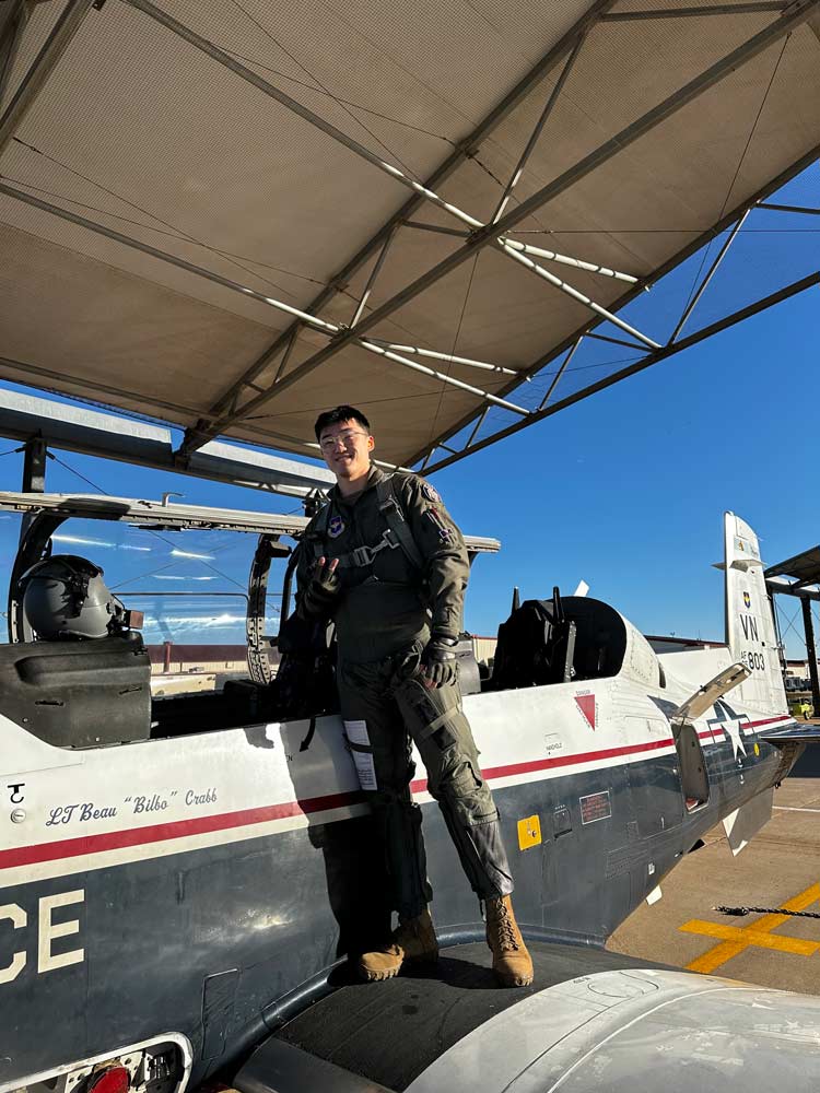 Kevin Qi stands outside an airplane posing