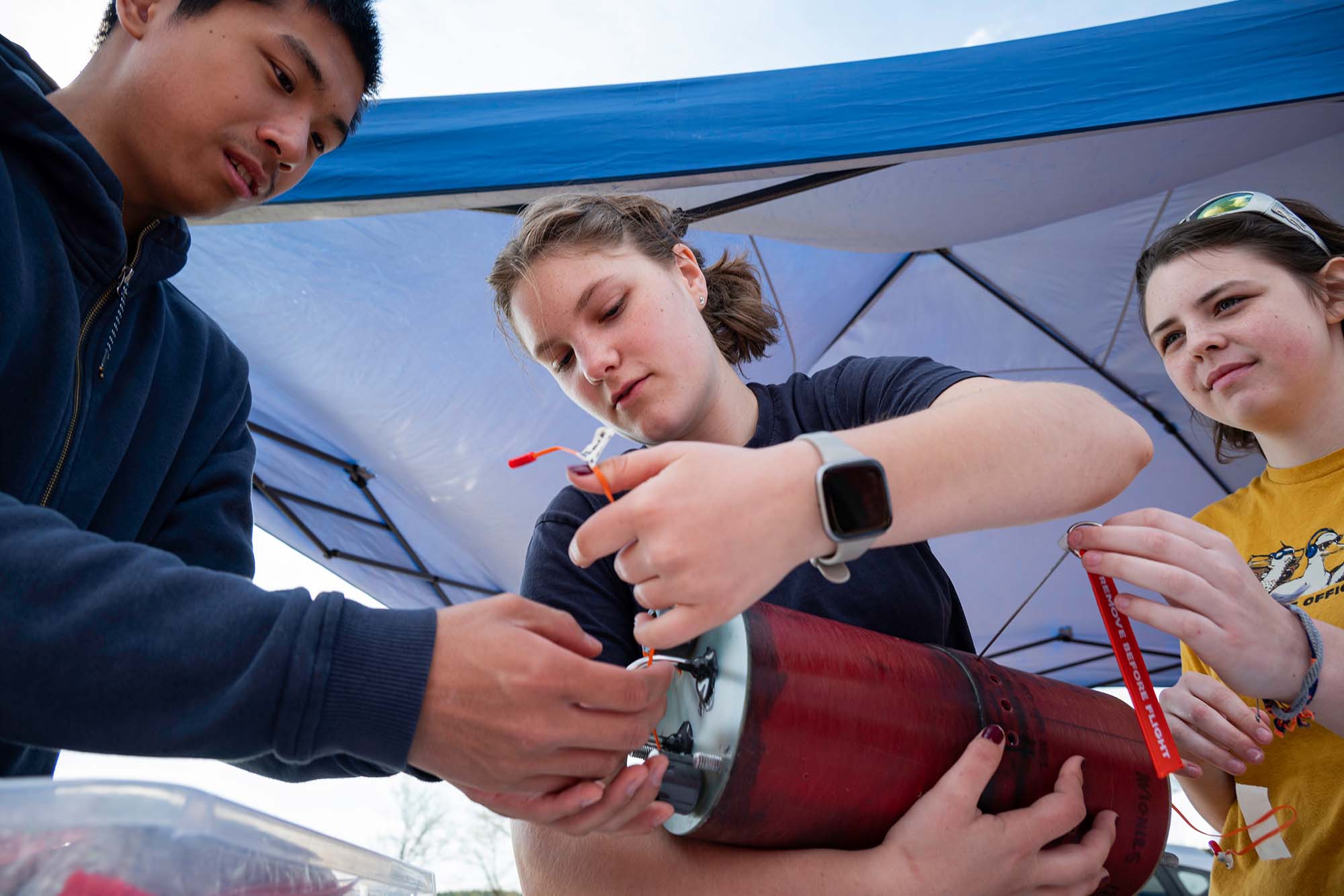 Anderson Wu, left, Jameson Phelps, center, and Olivia MacKenzie preparing an avionics bay.